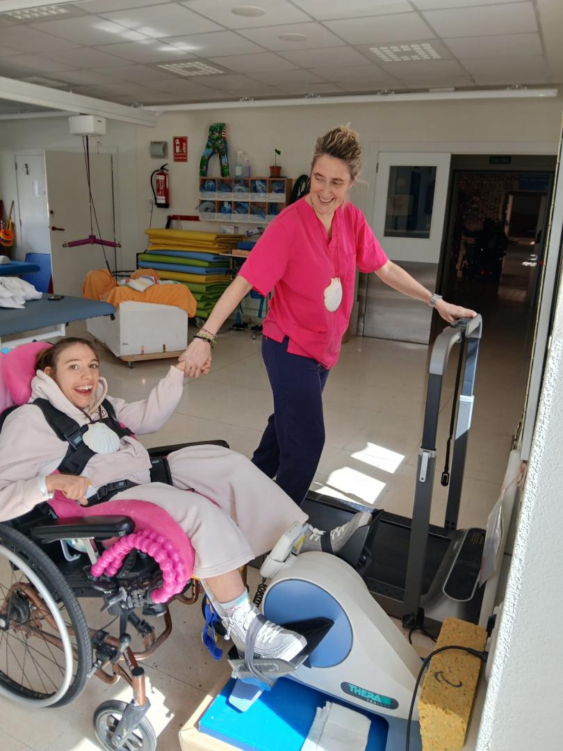 Lucía Turullols pedalea mientras la rehabilitadora Cristina Vizcay camina en una cinta