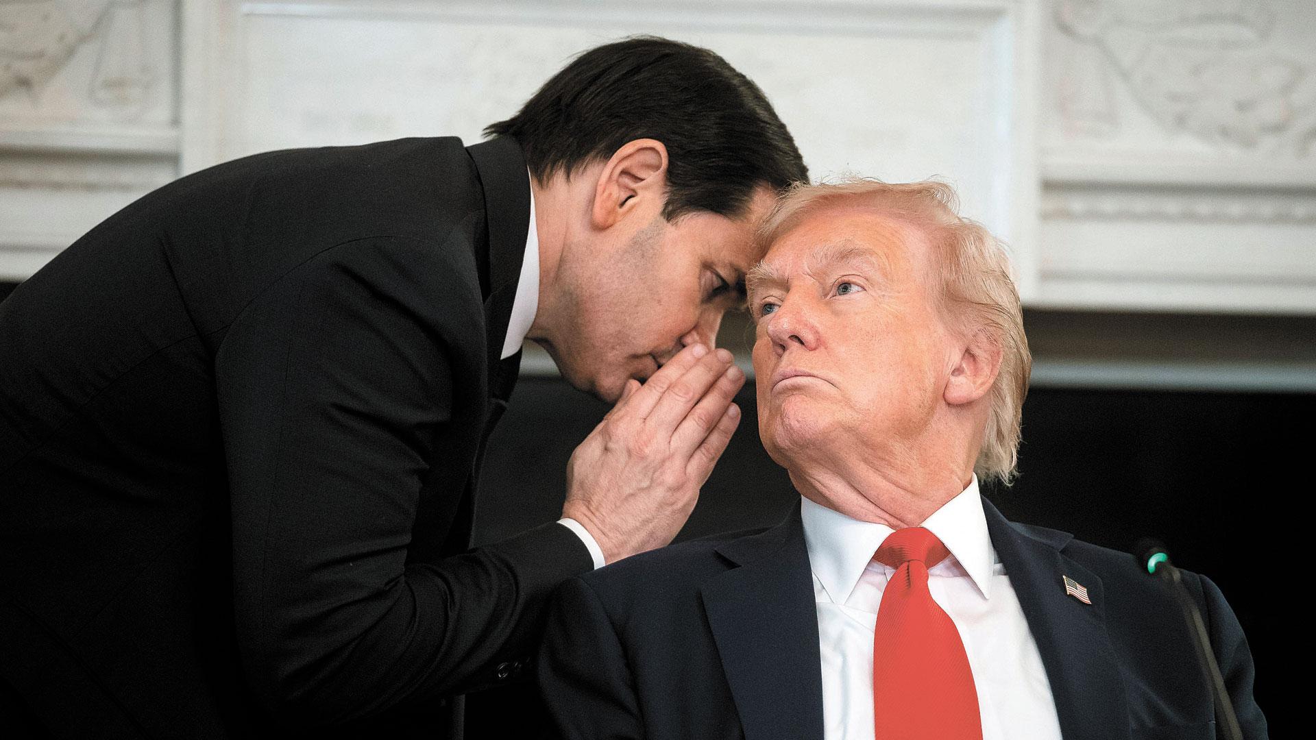 El secretario de Estado de EE UU, Marco Rubio, susurra al presidente Donald Trump,  en un comedor de la Casa Blanca en Washington