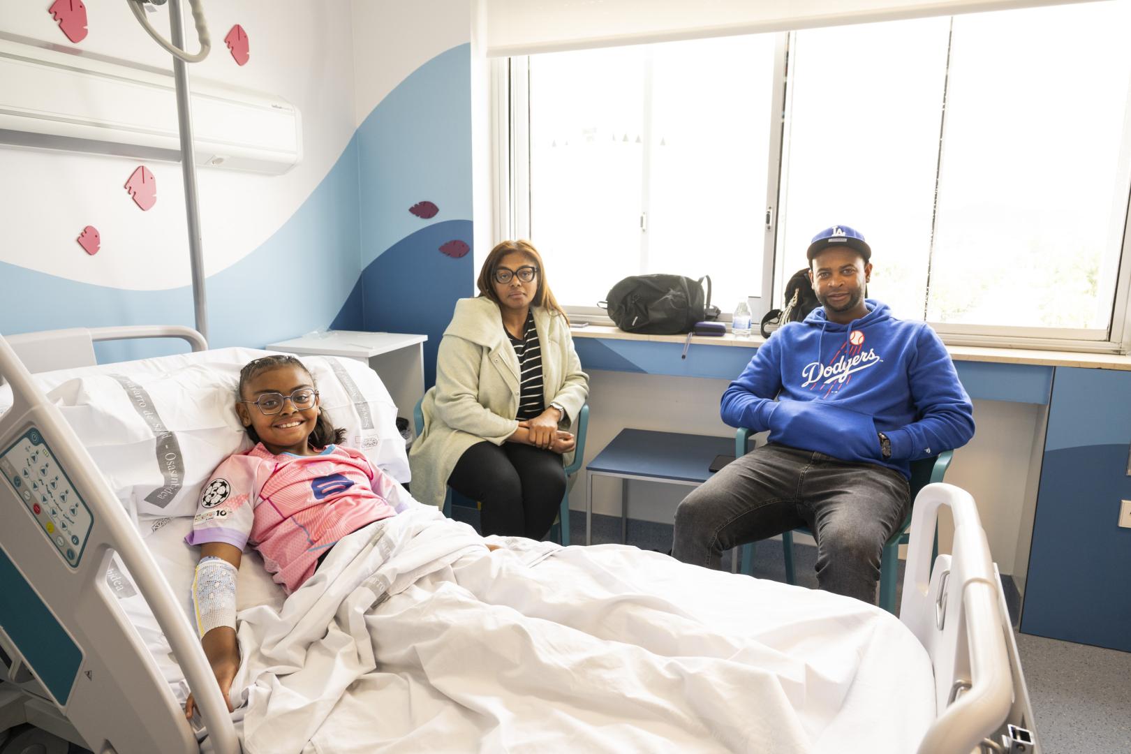 Edurne Rodríguez, en la cama de la Unidad del Paciente Crónico Complejo Pediátrico del HUN, con sus padres José y Deuzenete