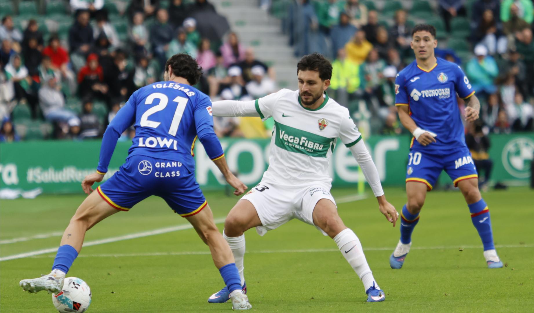 El defensa del Elche Víctor Chust disputa un balón con el defensa del Getafe Juan Iglesias durante el encuentro de la jornada 37