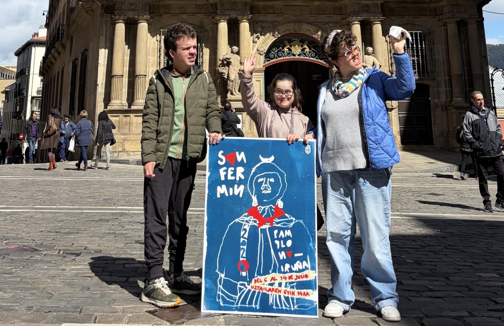 Iosu Zandio, Naiara Olaechea y June Zandio, con su cartel de San Fermín en la plaza del Ayuntamiento de Pamplona