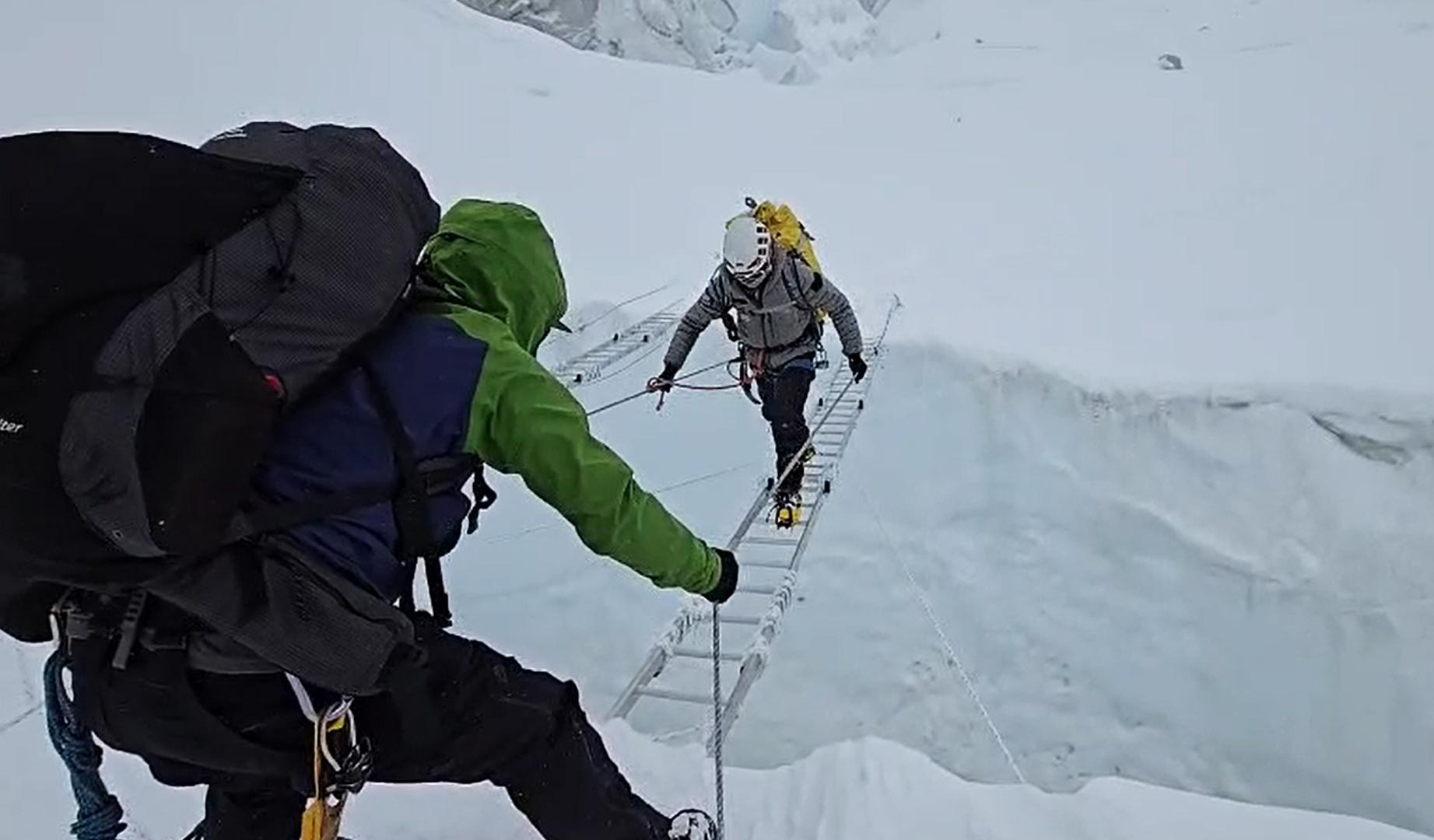 Un montañero cruza por una escalera fijas una de las tremendas grietas que existen en la Cascada del HIelo del Khumbu, un paso obligado en el ascenso por la ruta normal al Everest