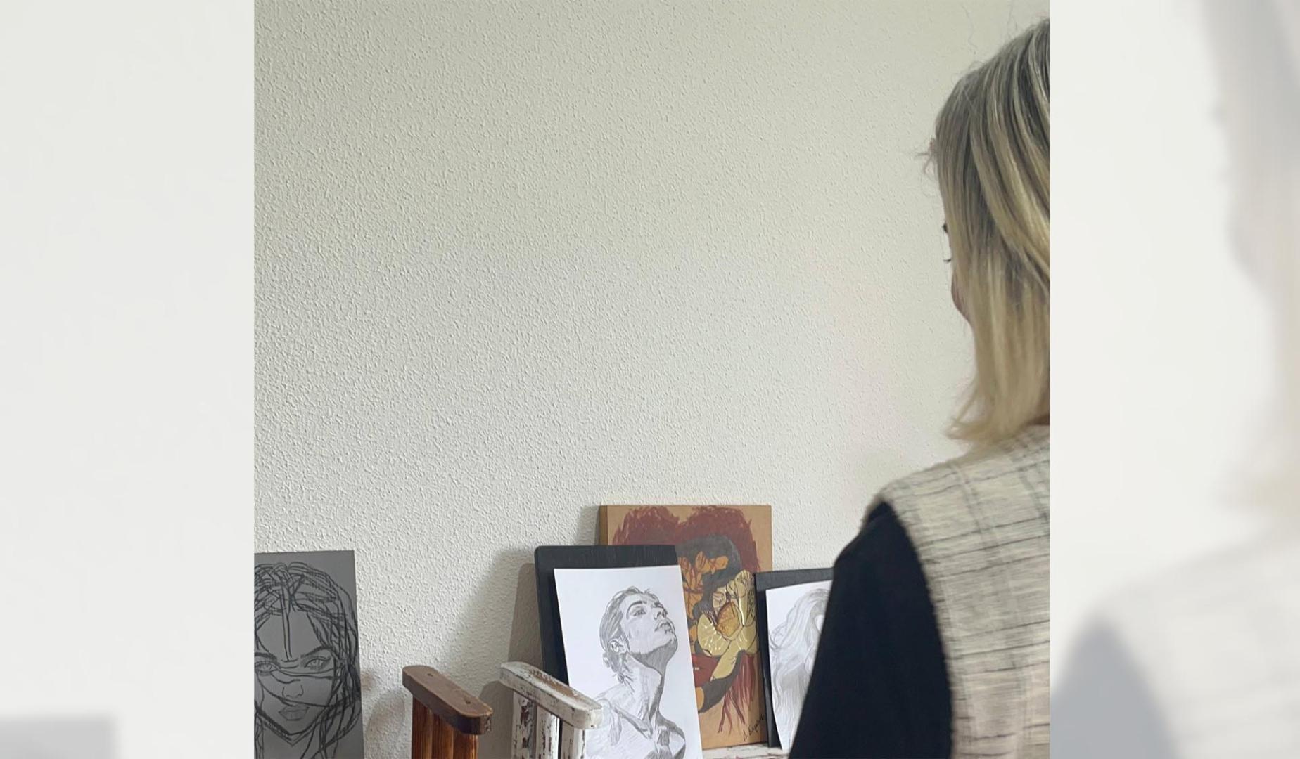 Una de las residentes en el cuarto que ocupa, lleno de las pinturas que ha hecho