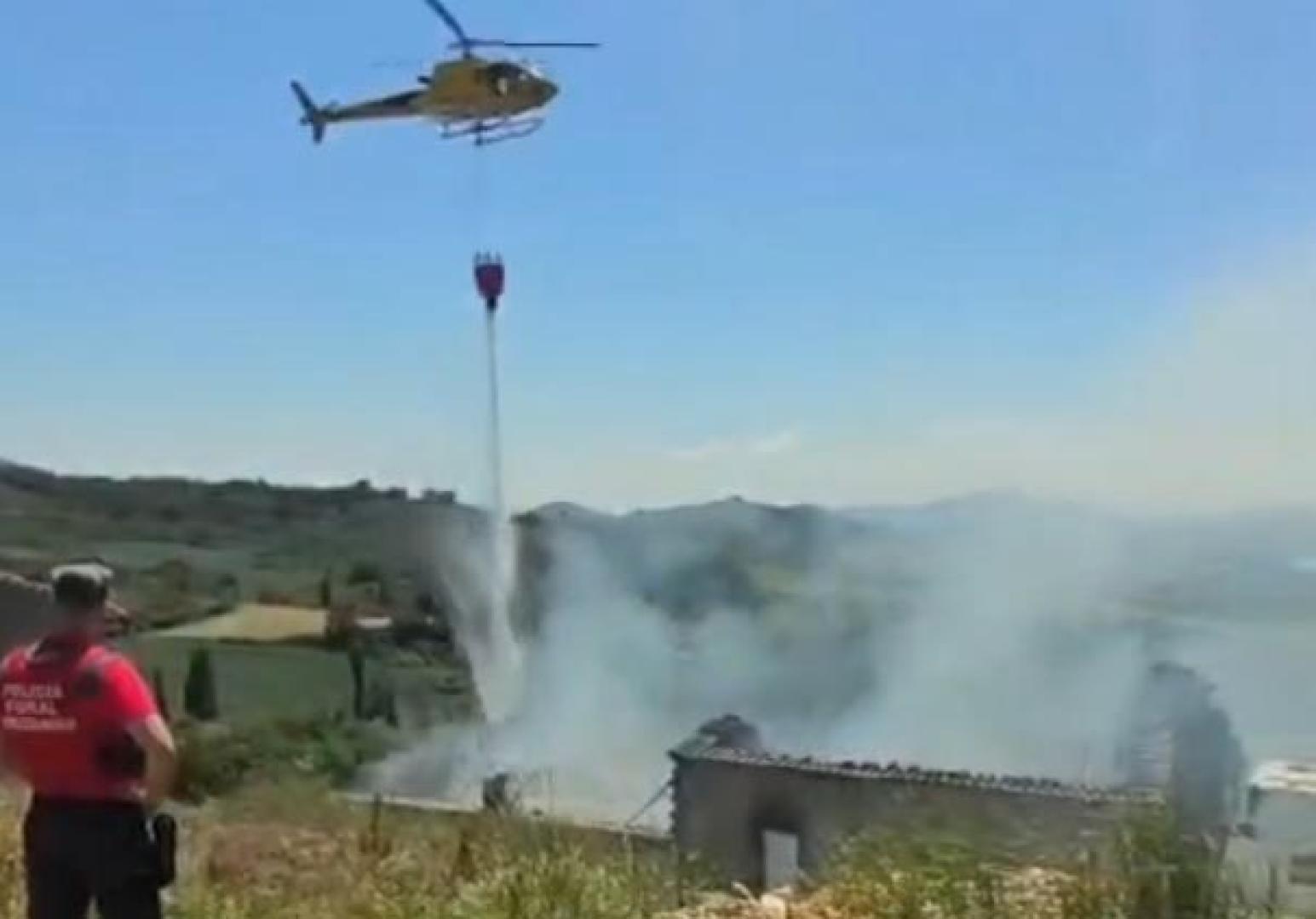 El helicóptero vierte agua sobre el cobertizo en llamas en Arzoz