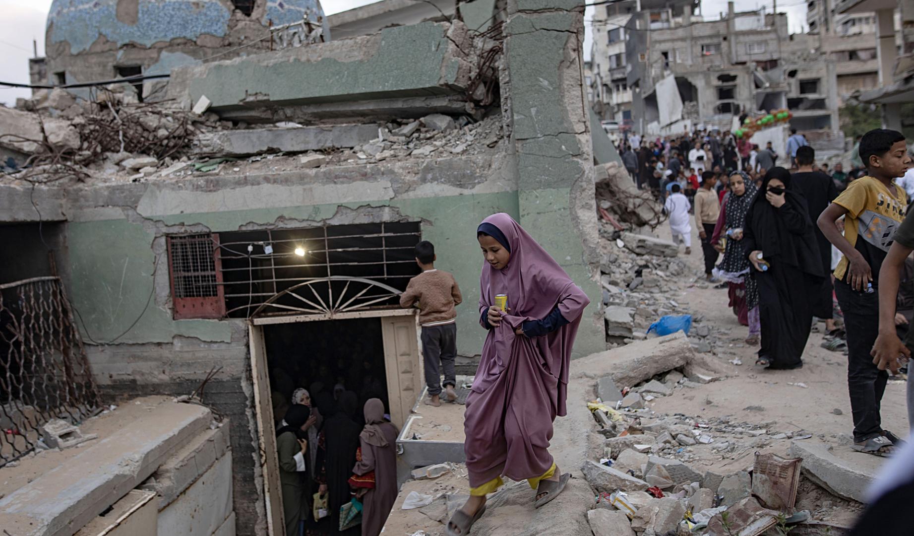 Refugiados palestinos entre los escombros de una localidad cercana a Gaza tras un bombardeo