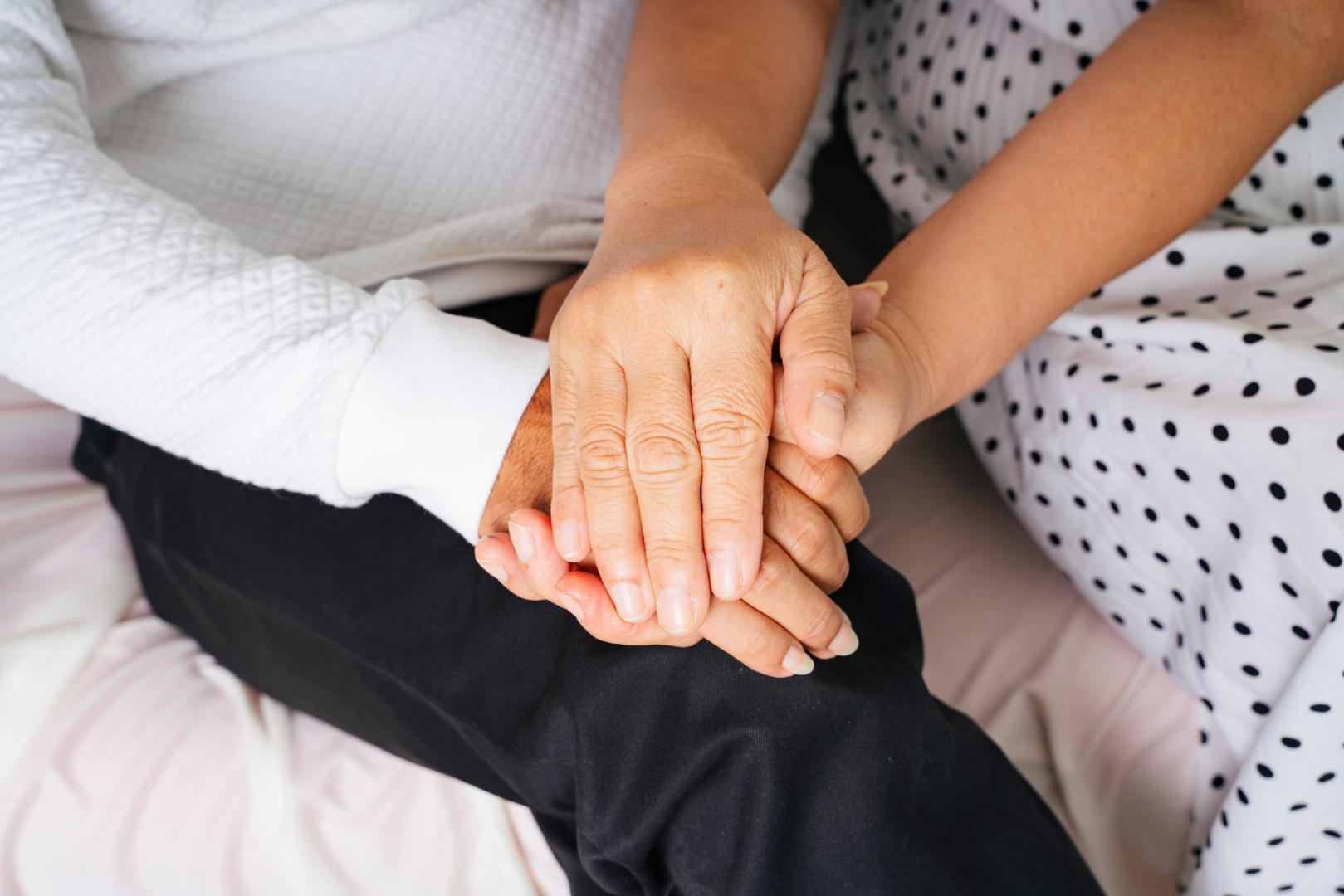 Close up - Old elderly senior couple holding hands with care and promise.