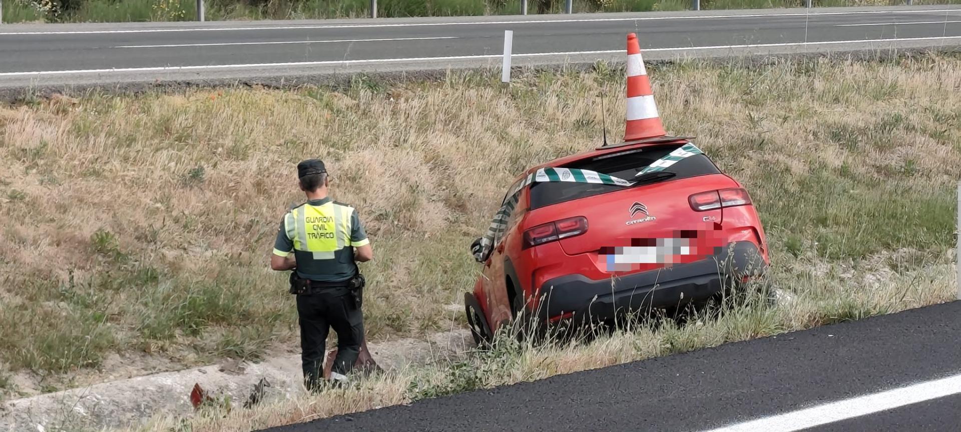 Un agente de la Guardia Civil, junto a uno de los vehículos accidentados
