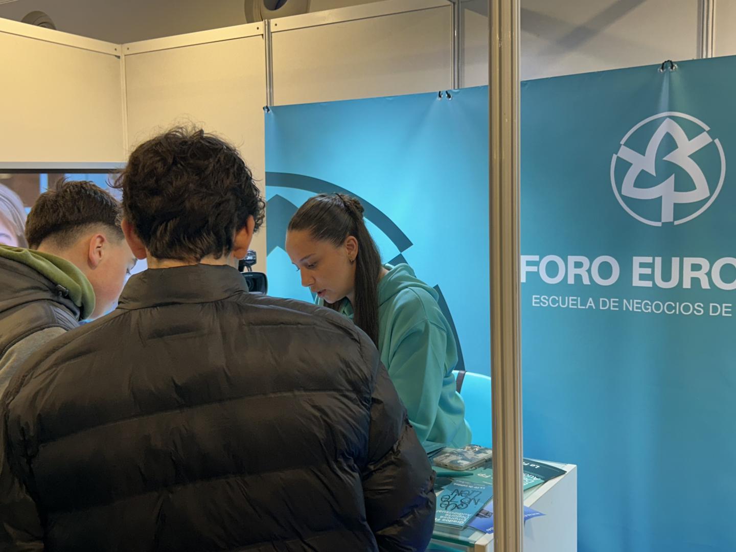 Dos jóvenes se acercan a un estand de Foro Europeo para obtener información sobre su oferta formativa