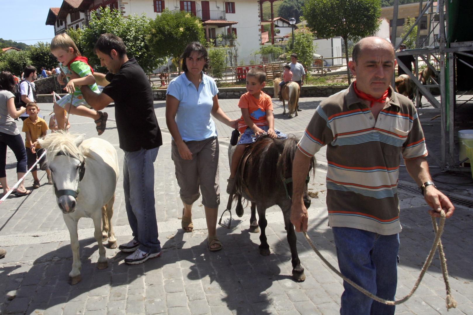 Dos menores pasean sobre sendas pottokas en una feria de Bera.