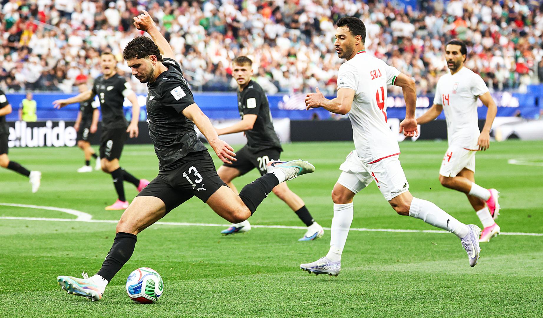 Liberato Cacace, de Nueva Zelanda, busca el disparo a portería entre rivales de Irán durante el encuentro del Mundial