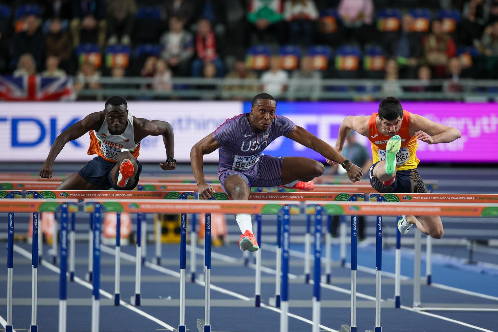 Asier Martínez, peleando junto a Badamassi (izda) y Beard, durante la serie clasificatoria. El navarro hizo 7.65. EFETorun (Poland), 21/03/2026.- (L-R) Badamassi Saguirou of Nigeria, Dylan Beard of USA and Asier Martinez of Spain compete in the Men's 60 Metres hurdles at the World Athletics Indoor Championships in Torun, Poland, 21 March 2026. (Mundial de Atletismo, Polonia, España) EFE/EPA/Lukasz Gagulski POLAND OUT