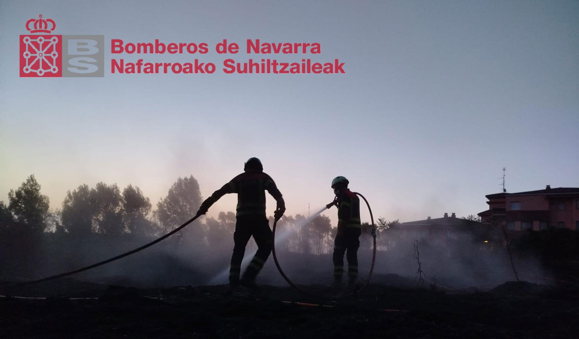 Dos bomberos trabajan en el incendio que ha afectado a un talud cerca del casco urbano de Lerin