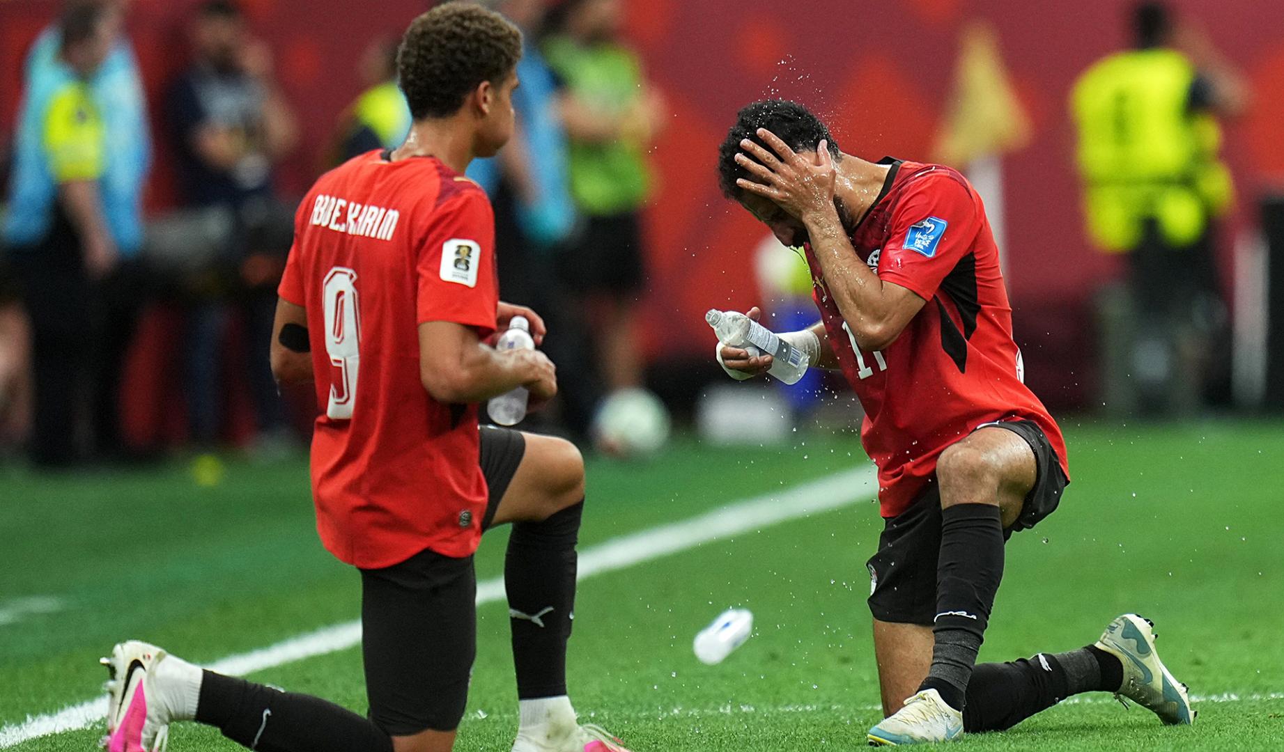 Hamza Abdelkarim (izda.) y su compañero Mohanad Lasheen beben en una pausa durante un partido de Egipto en el Mundial