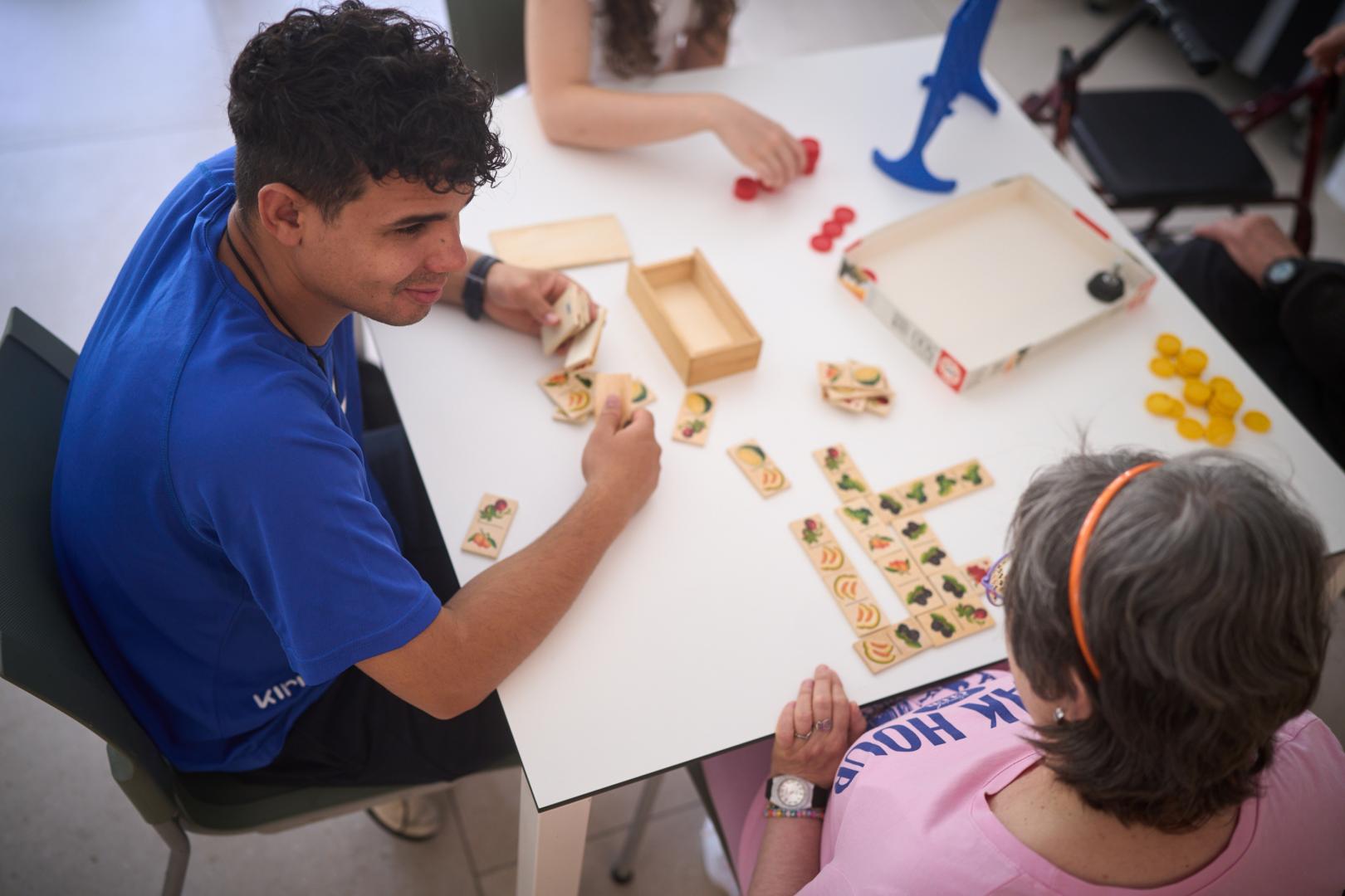 El escolapio Pedro Díaz, de la Fundación Itaka, juega a un juego de mesa con una usuaria