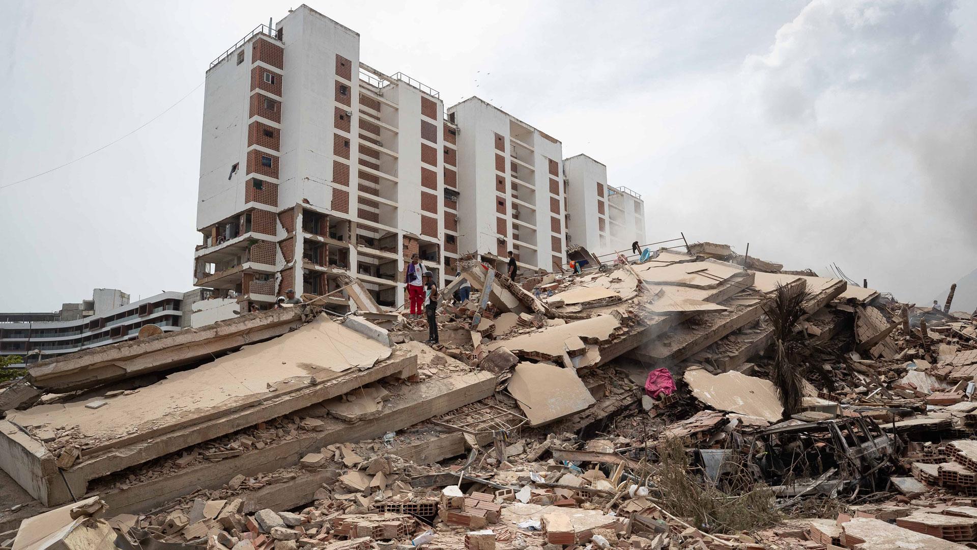 Personas caminan por los escombros de edificios afectados por los terremotos que se han producido este jueves, en La Guaira (Venezuela)