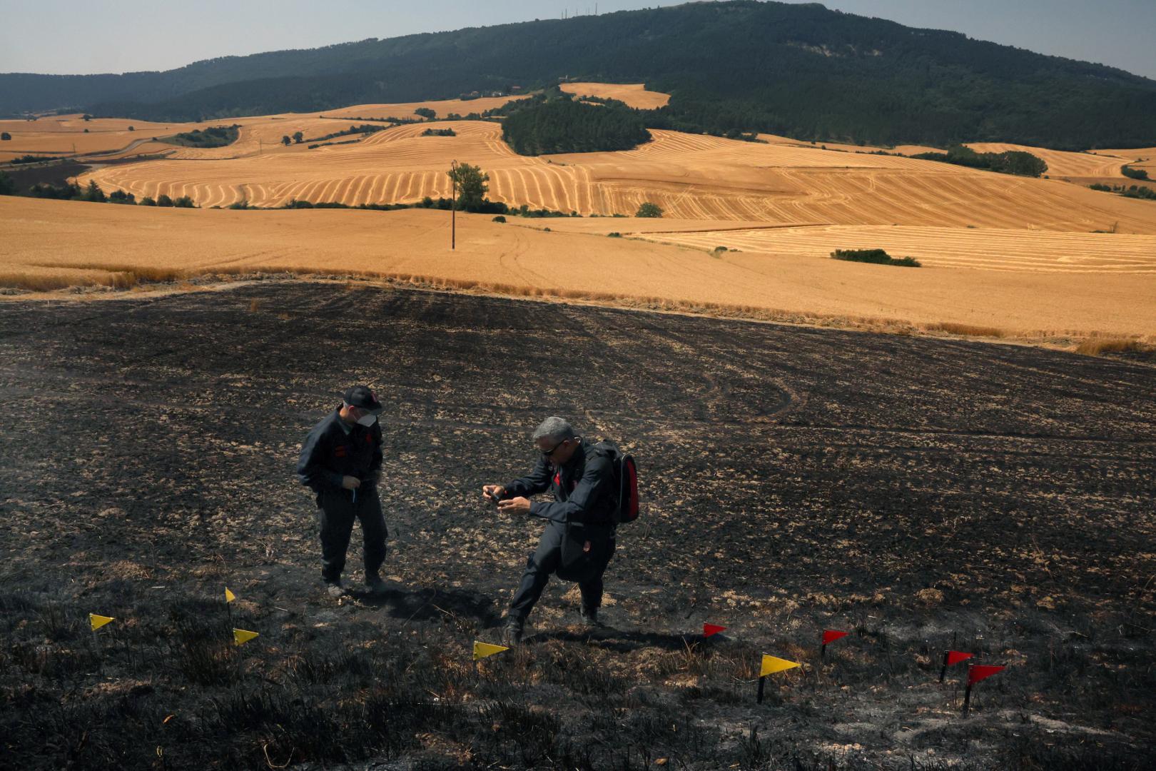 Agentes de la Policía Foral trabajan en el lugar donde empezó el fuego, un campo de cereal sin cosechar entre Makirriain y Orrio