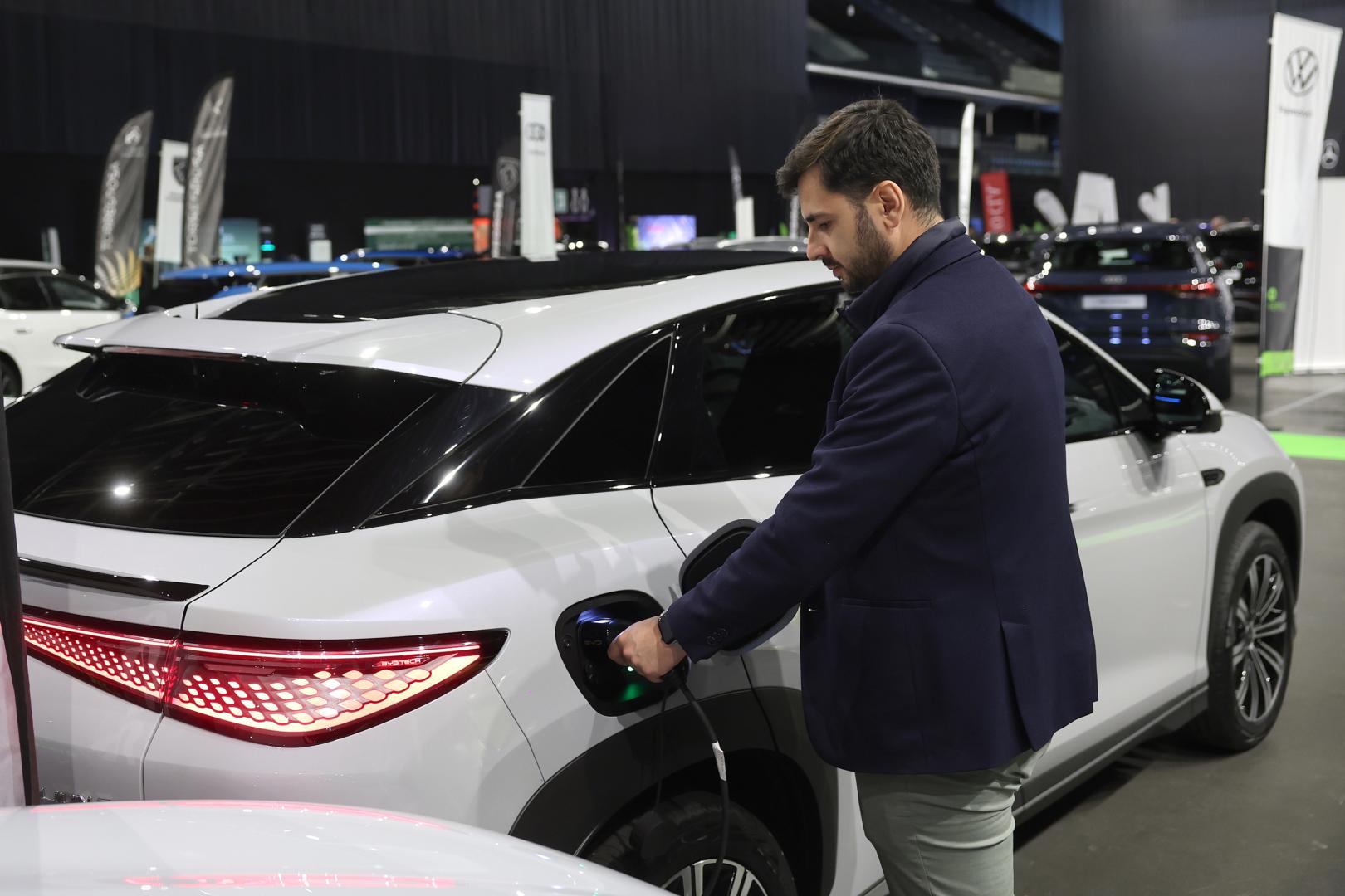 Una persona enchufa un coche eléctrico chino expuesto en la feria Ecomovers