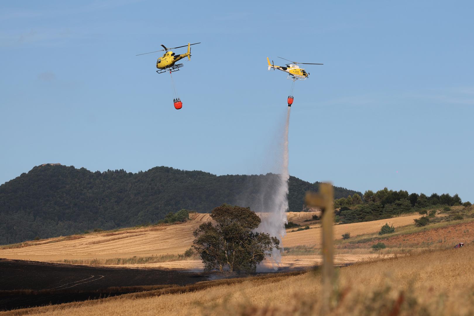 Dos helicópteros trabajando sobre un incendio declarado en un campo de cereal de Badostain