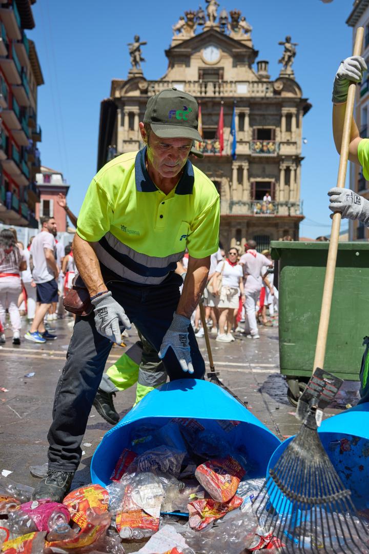 Asiáin recoge de uno de los cientos de cubos que salieron de la plaza tras el Chupinazo.