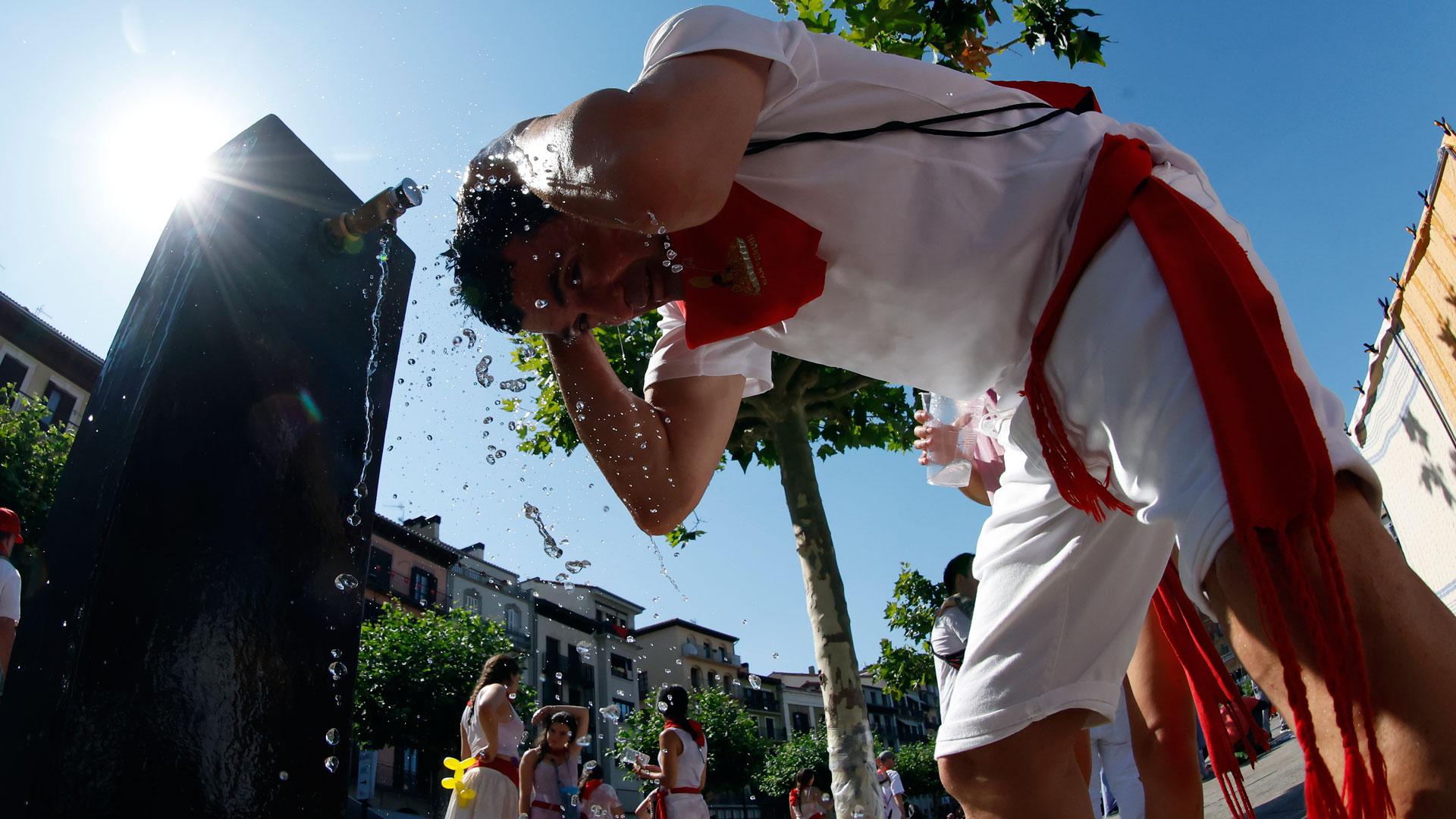 Un joven se refresca del calor en una de las fuentes de la Plaza del Castillo de Pamplona