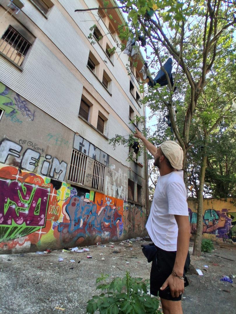 Un residente del edificio abandonado muestra la ventana desde la que cayó.