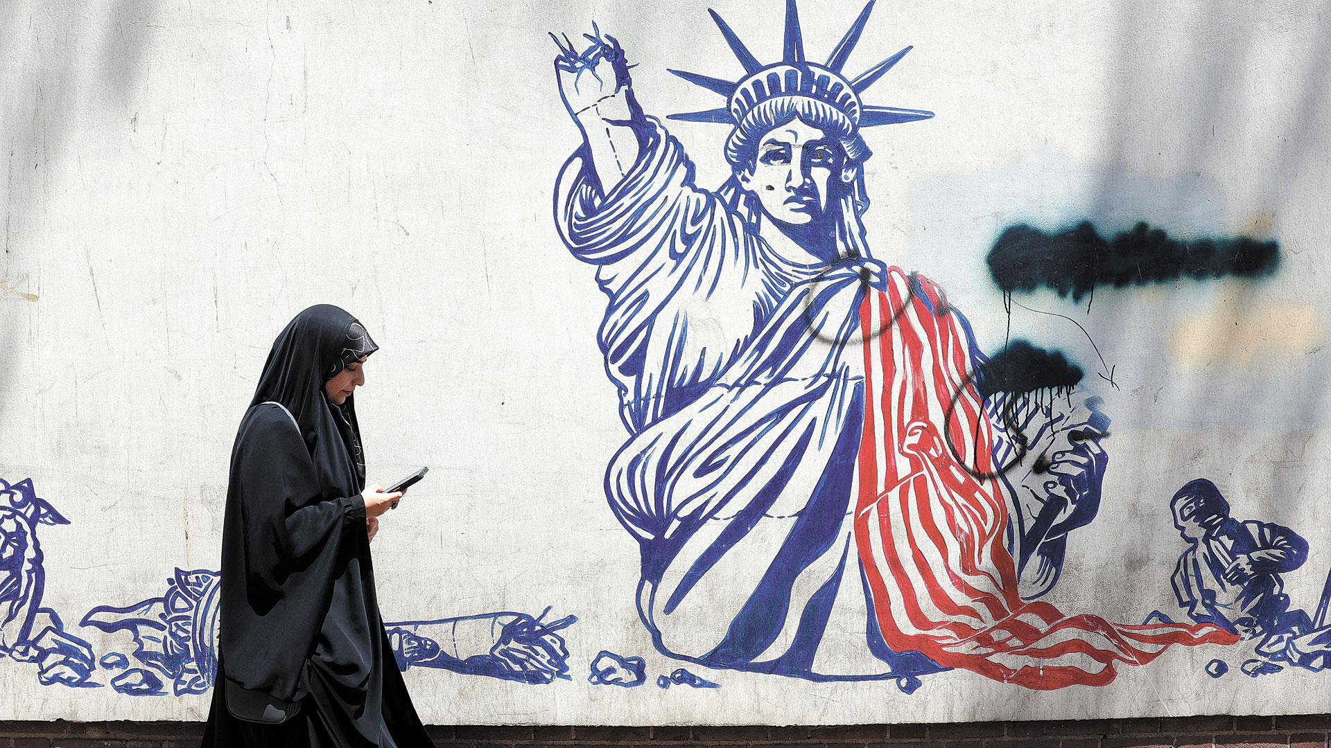 Una mujer pasa delante de una pintada antinorteamericana en el edificio donde estuvo la embajada de EE UU en Teherán
