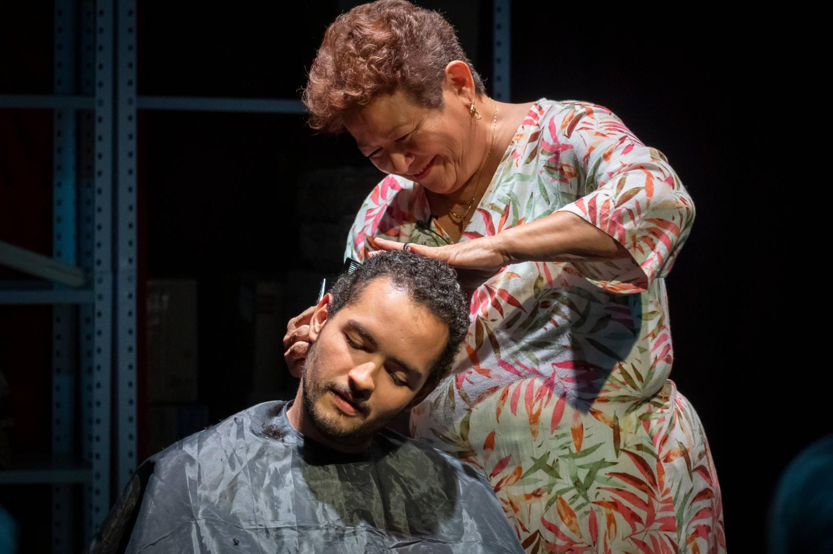 Josefina Orlaineta corta el pelo a su hijo, Anacarsis Ramos, en 'Mi madre y el dinero', obra en la que reproducen algunos de los cuarenta trabajos que ha tenido ella, como este de peluquera