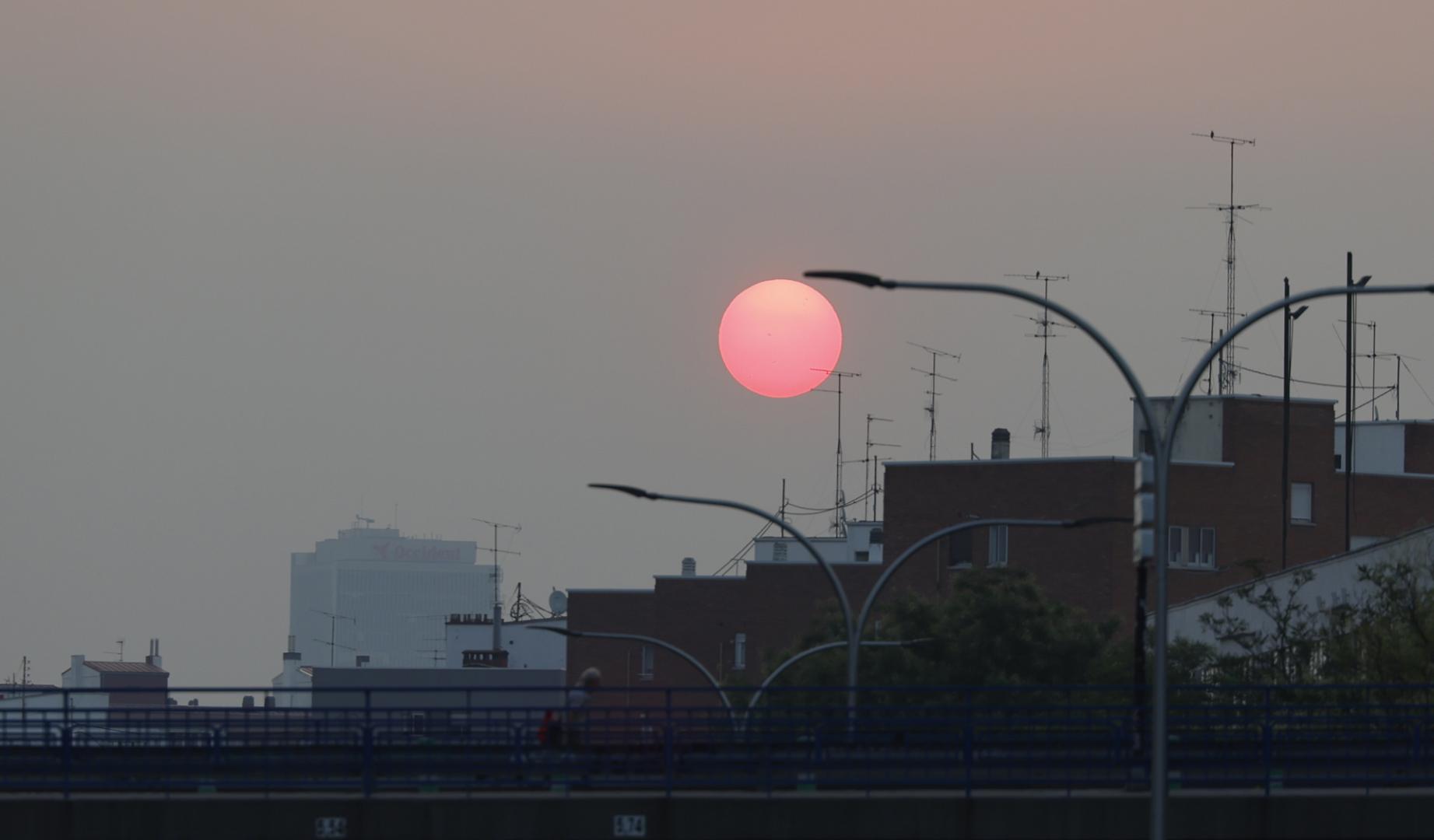 Vista del amanecer desde Plaza Elíptica con un manto de ceniza sobre Madrid este sábado debido a los incendios forestales que asolan la comunidad