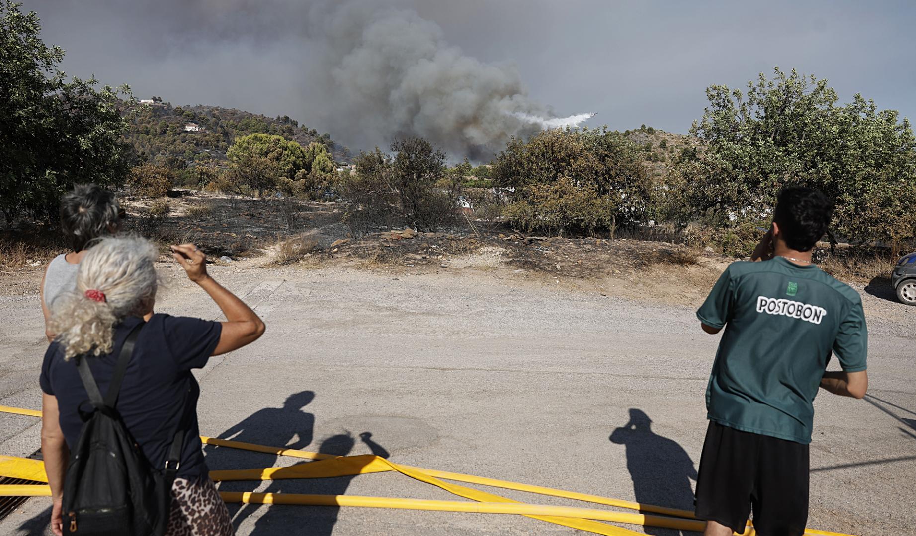Varias personas observan la pelea contra las llamas en el incendio de La Vall d'Uixò (Castellón)