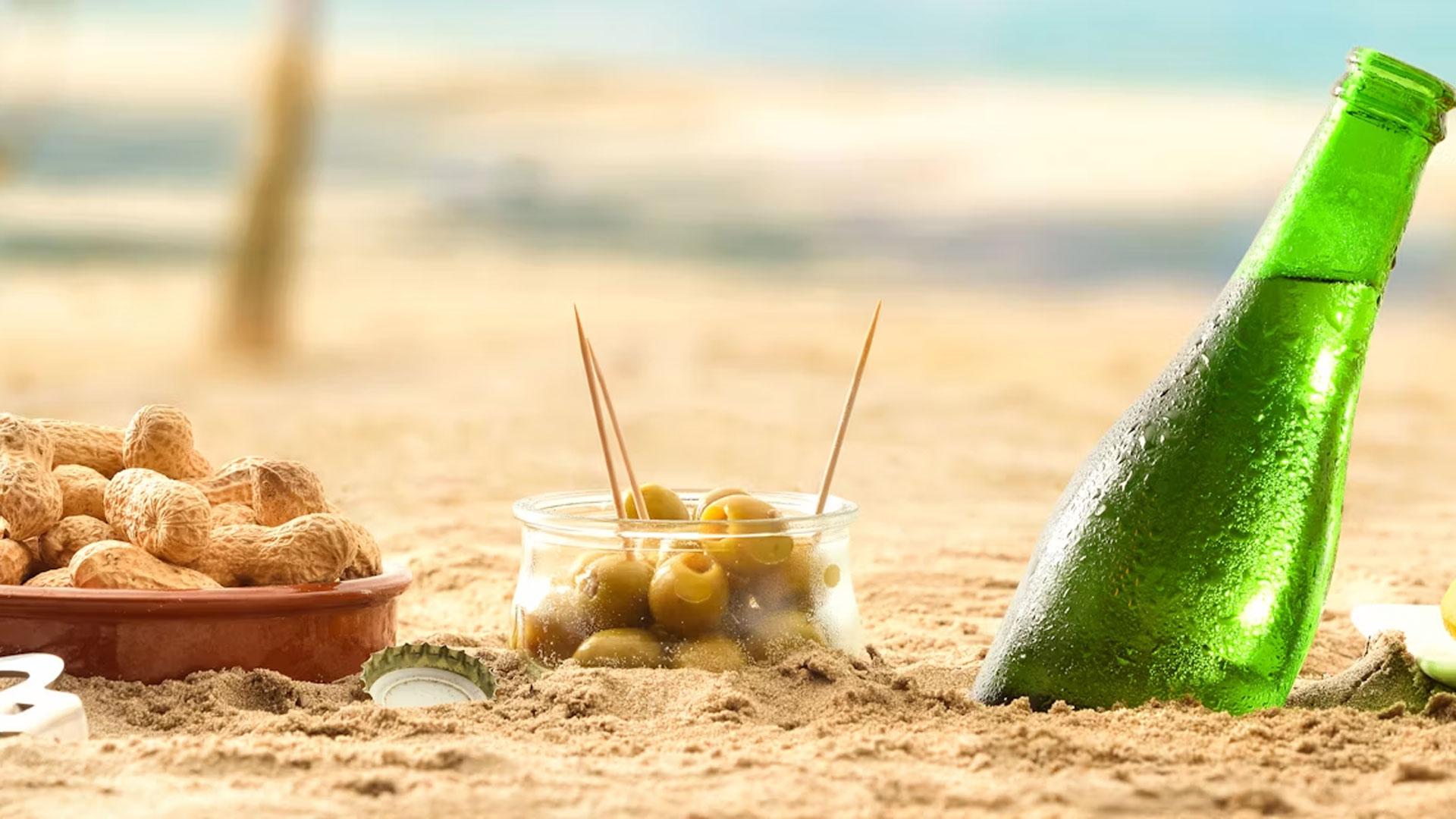Un aperitivo en la playa con una cerveza, aceitunas y cacahuetes