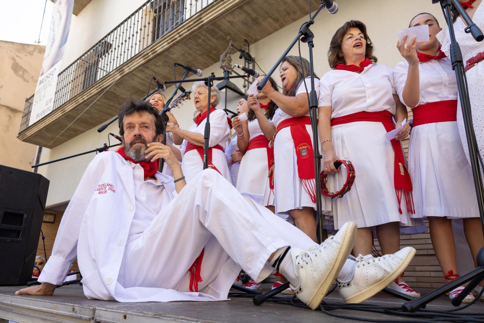 Miguel Ángel Calvo Buttini, Tudelano Ausente 2026, sentado en la tarima mientras le dedican una jota alusiva