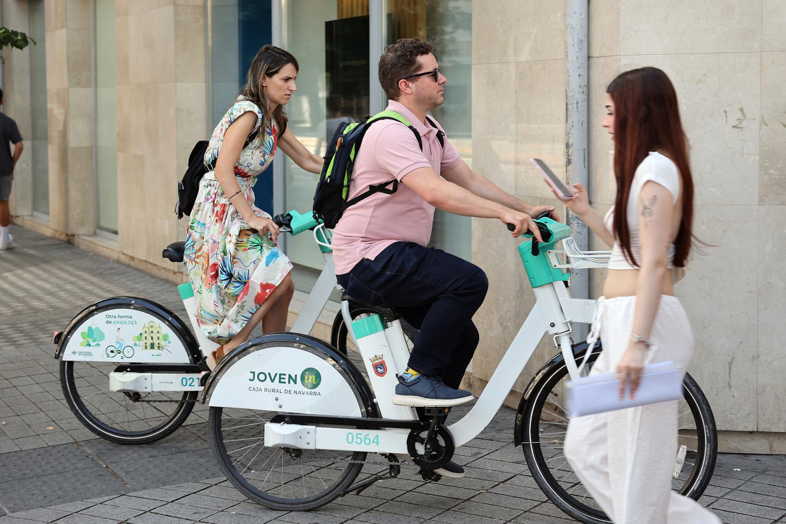 Imagen de archivo del pasado verano con dos personas circulando por Pamplona con las bicicletas del servicio municipal de alquiler
