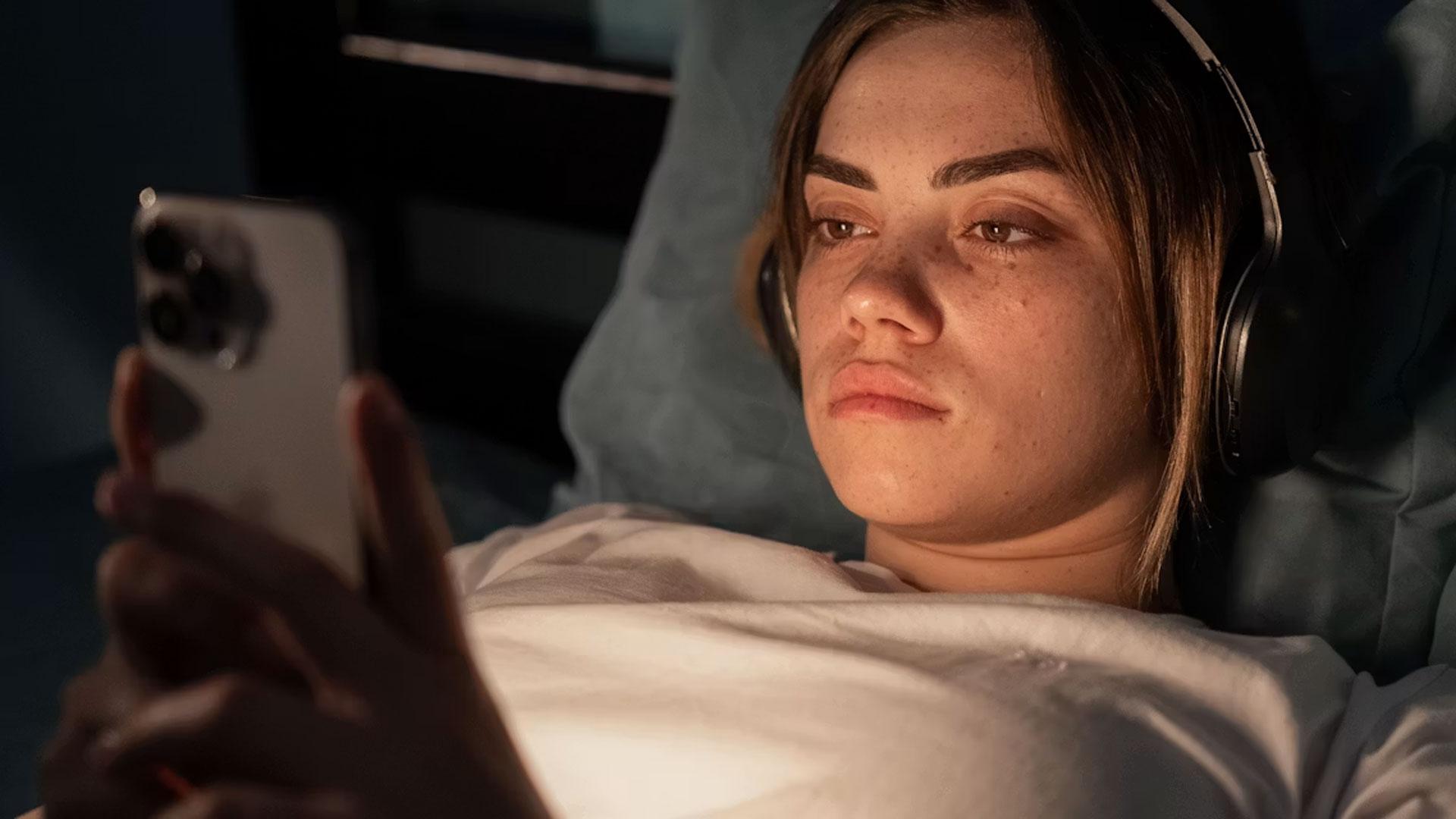 Una joven mirando el móvil en la cama antes de dormir