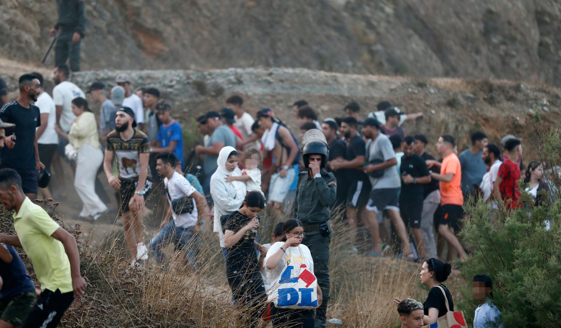 Imagen de personas escapando este jueves de las fuerzas antidisturbios marroquies que han desalojado a las masas que se encontraban cerca de la frontera con Ceuta.