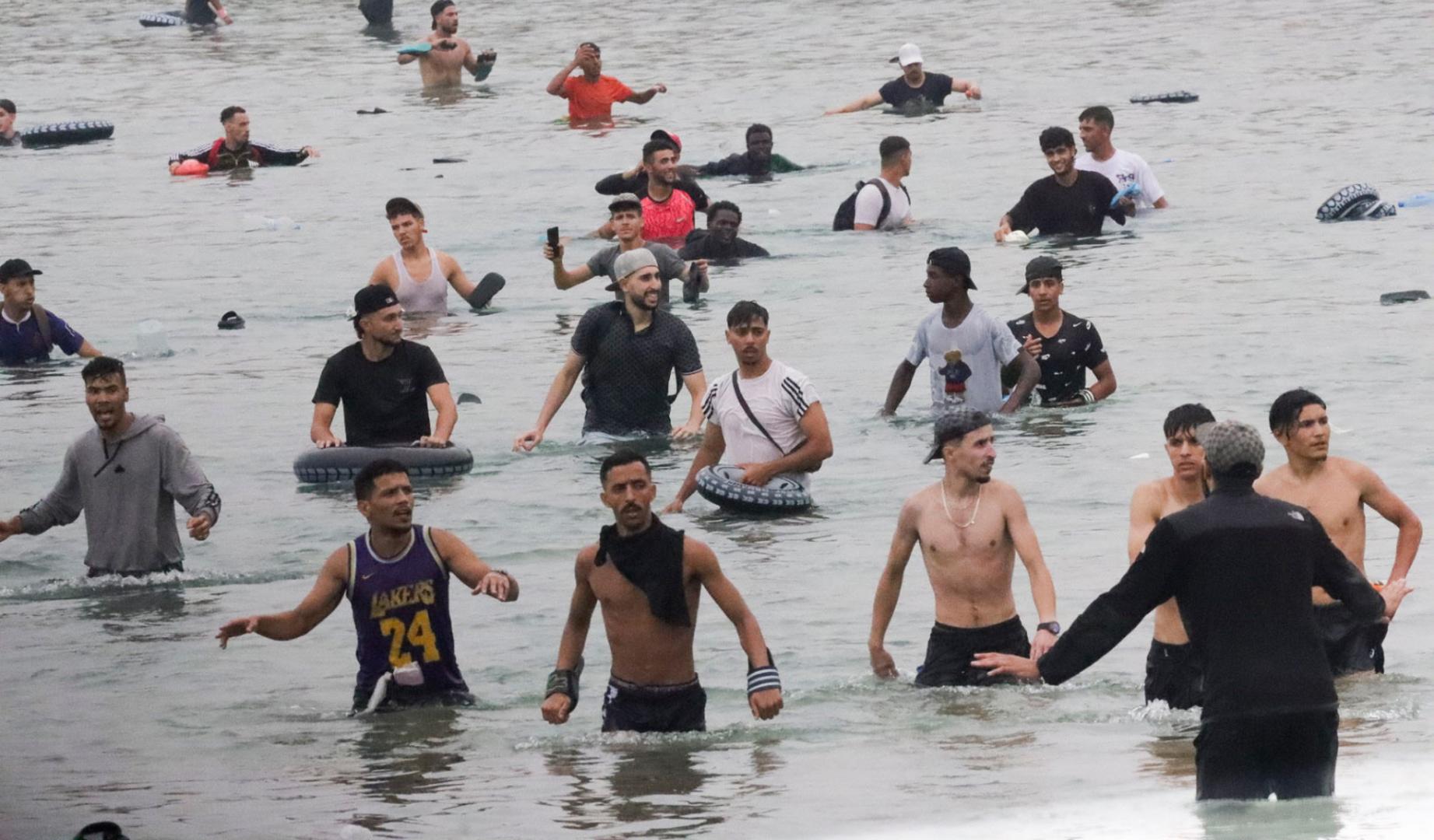 Un grupo de inmigrantes en la playa junto al paso fronterizo del Tarajal en Ceuta