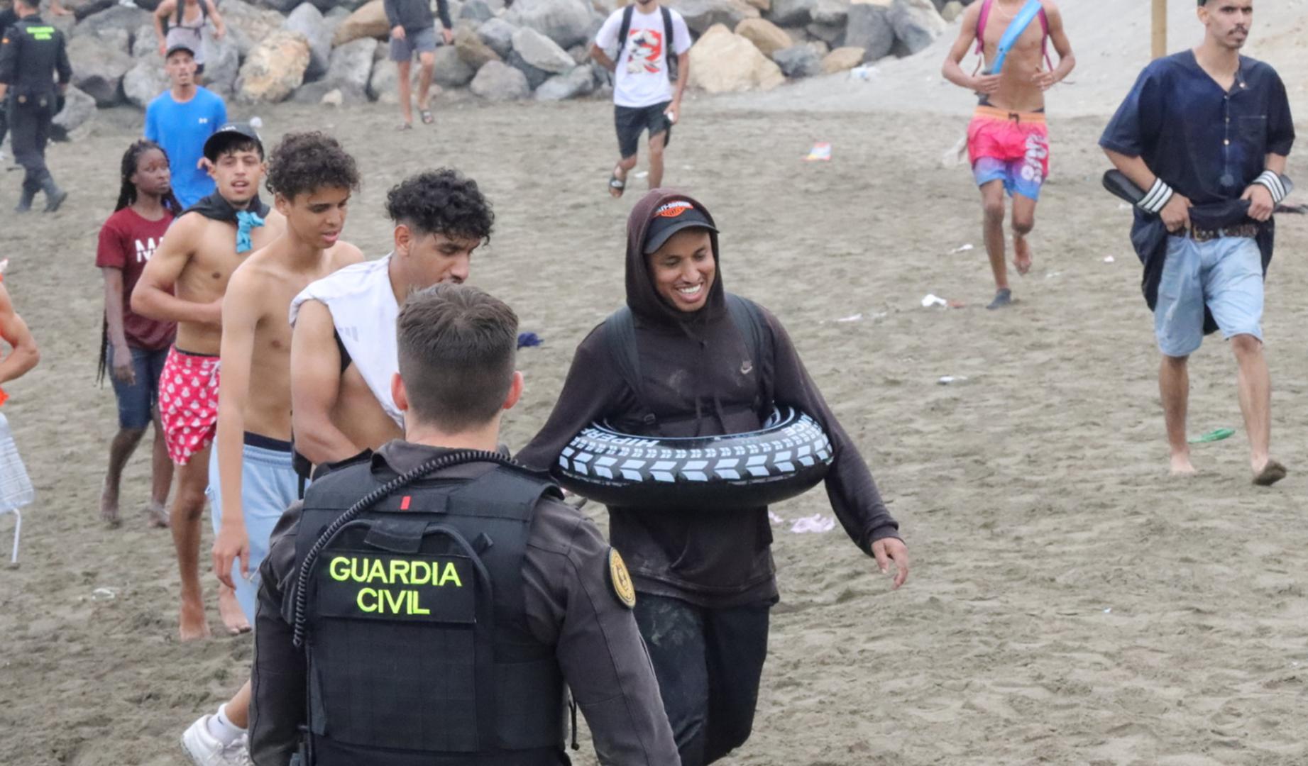 Un grupo de inmigrantes en la playa junto al paso fronterizo del Tarajal en Ceuta este viernes,