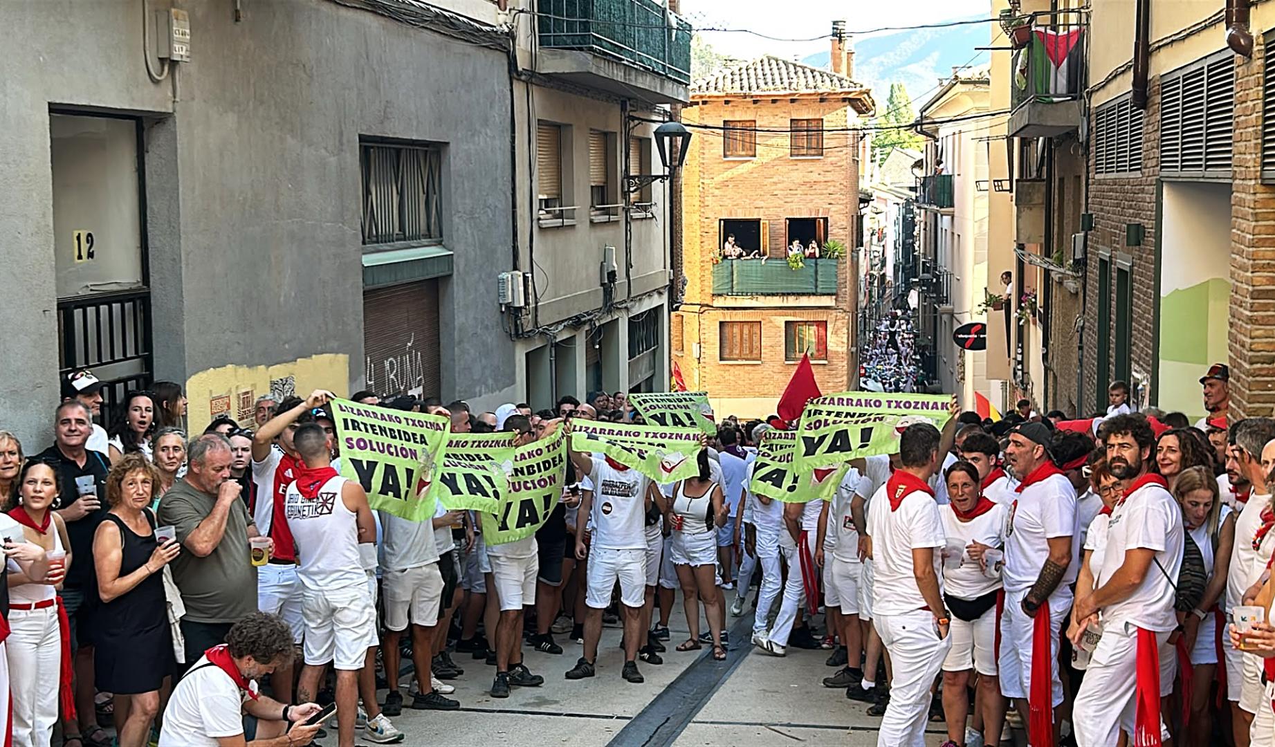 varias personas sujetan pancartas de protesta por las txoznas este viernes, 31 de julio, en Estella
