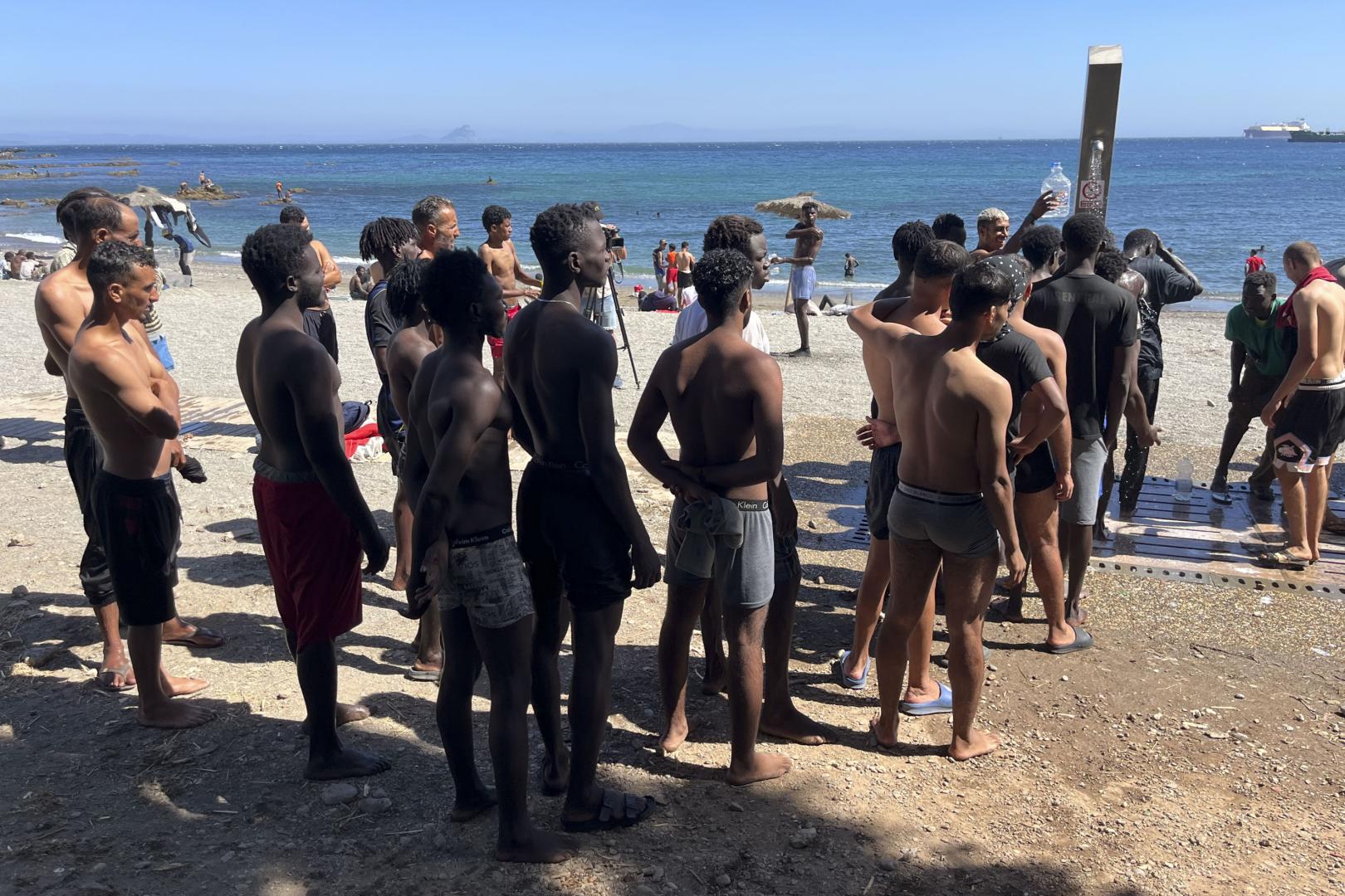 Los jóvenes inmigrantes que duermen en la calle hacen cola para ducharse en la playa del Trampolín, tras acceder a Ceuta el pasado jueves durante la entrada masiva por el espigón fronterizo protagonizada por más de 70.000 personas y que permanecen en la ciudad, entre ellos 528 menores