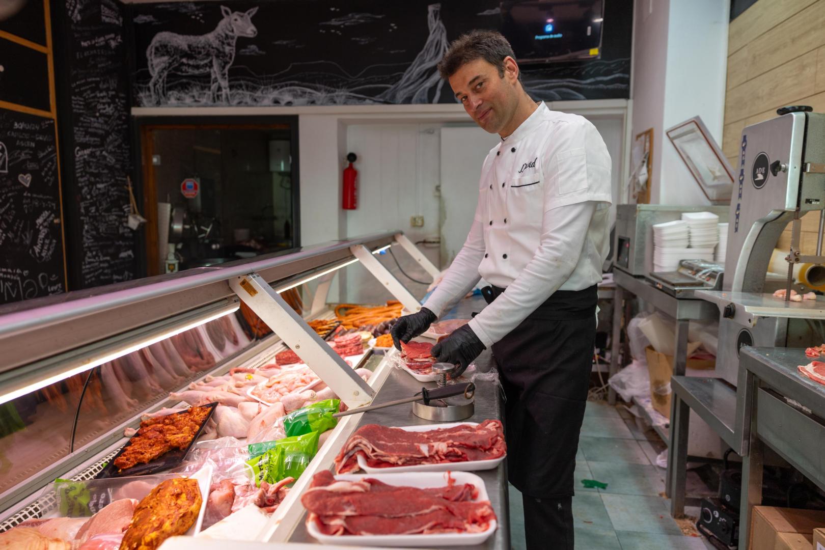 El carnicero muestra sus productos tras el mostrador de su local