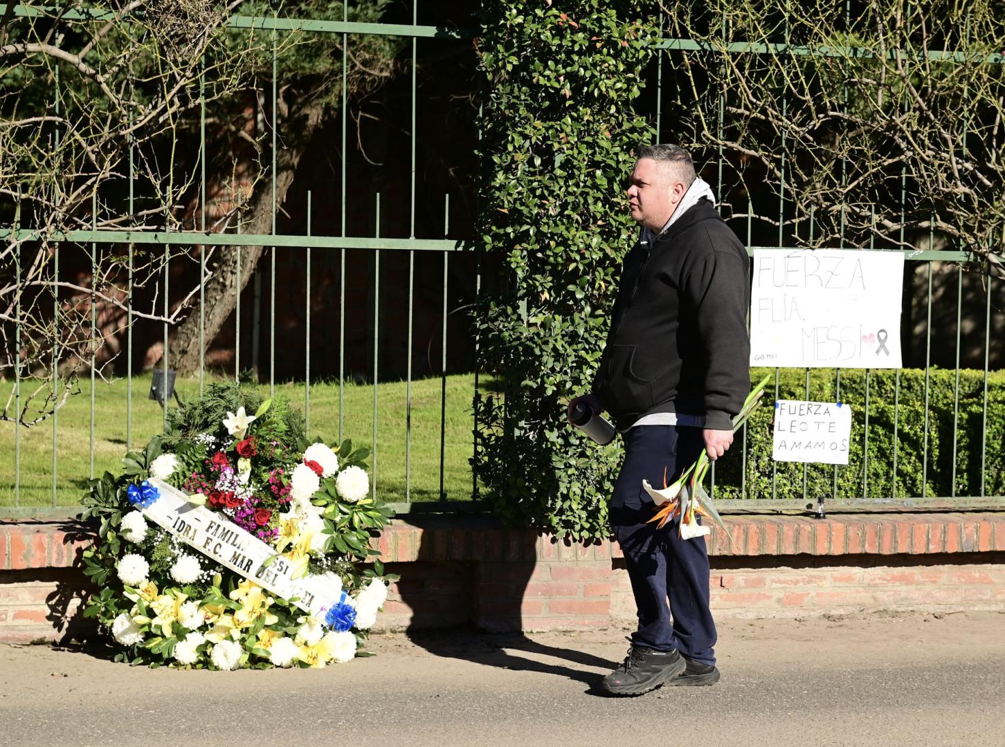 Una persona camina llevando un ramo de flores frente al cementerio privado El Prado, este domingo en Rosario (Argentina)