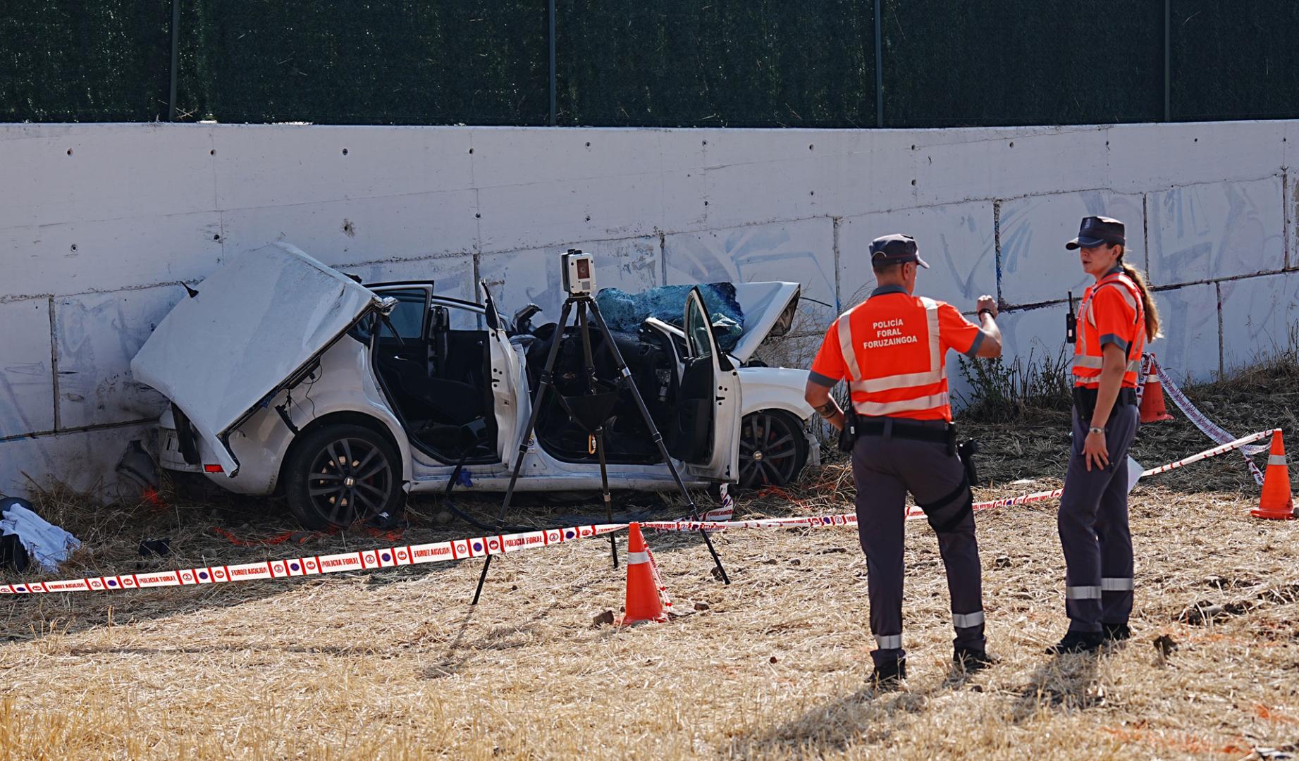 Dos agentes de Policía Foral, junto al vehículo accidentado en el que viajaban dos personas que han perdido la vida este jueves en Beriain