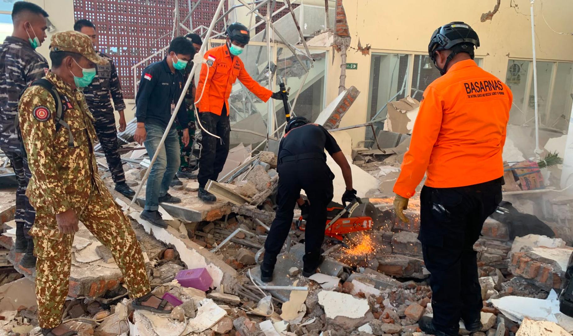 Fotografía cedida por la Agencia Nacional de Búsqueda y Rescate de Indonesia (Basarnas) de sus integrantes trabajando en un edificio derrumbado tras un terremoto de 7,7 registrado este sábado, en la isla de Flores