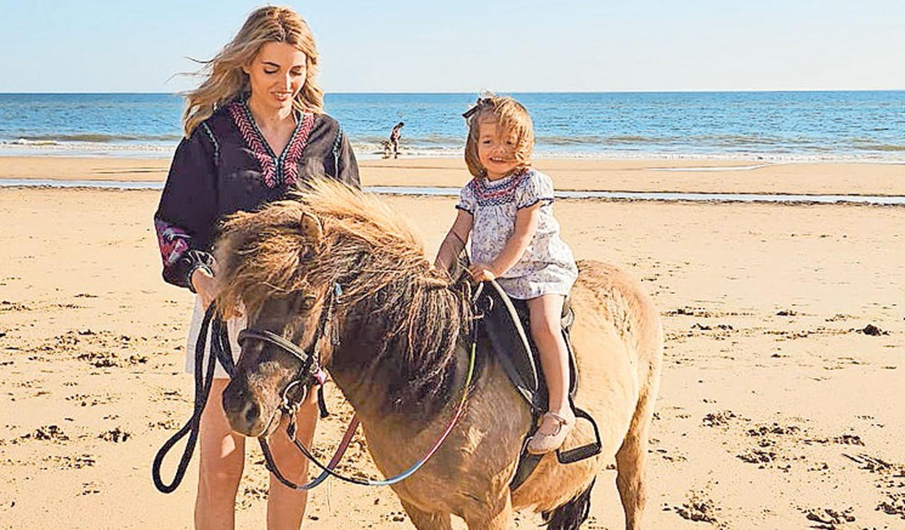 Nerea Berraondo en la playa de Matalascañas junto a su hija Sara, de 4 años, a lomos del poni Barbas