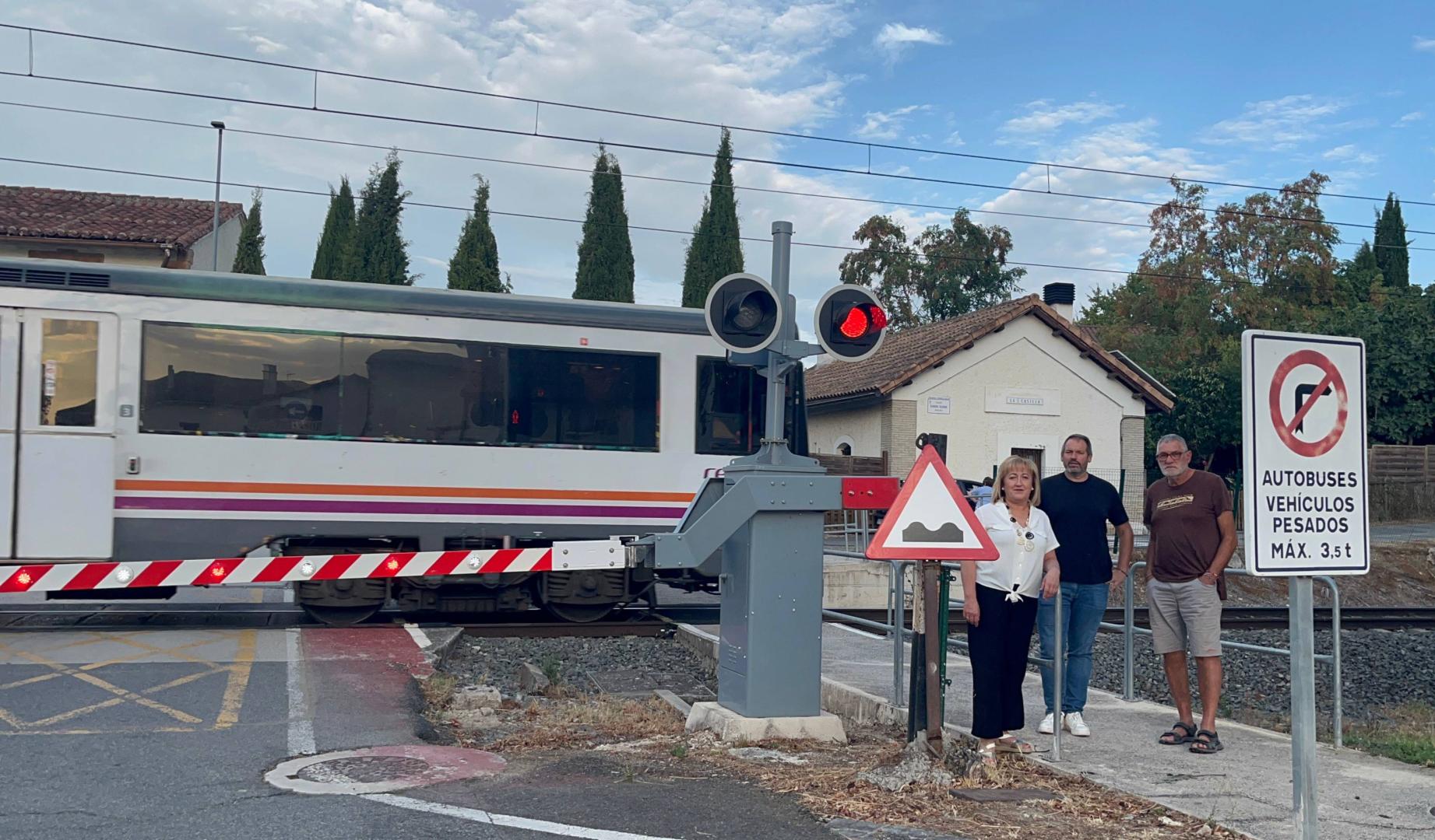 Mari Carmen Tirapu, Óscar Amóztegui e Iñaki Martínez posan junto al paso a nivel mientras circula un tren de pasajeros por Esquíroz.