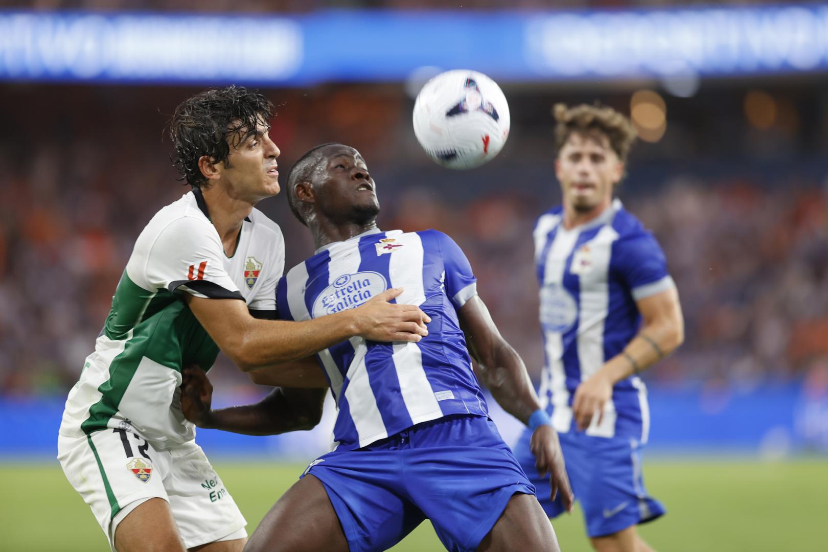 El centrocampista camerunés del Deportivo Nsongo Bil disputa un balón con Gonzalo Villar, del Elche