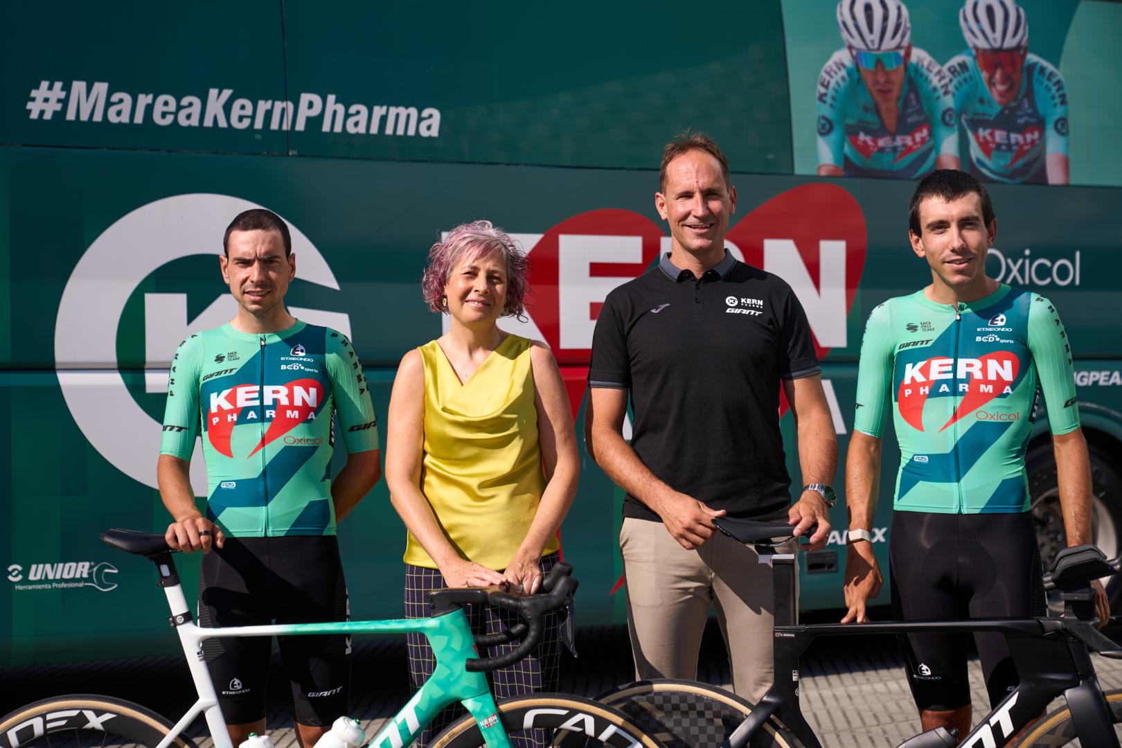 Los ciclistas Ibon Ruiz y Diego Uriarte flanquean, delante del autobús del equipo, a Rebeca Esnaola (consejera del Gobierno de Navarra) y a Juanjo Oroz (mánager general del Kern Pharma).
