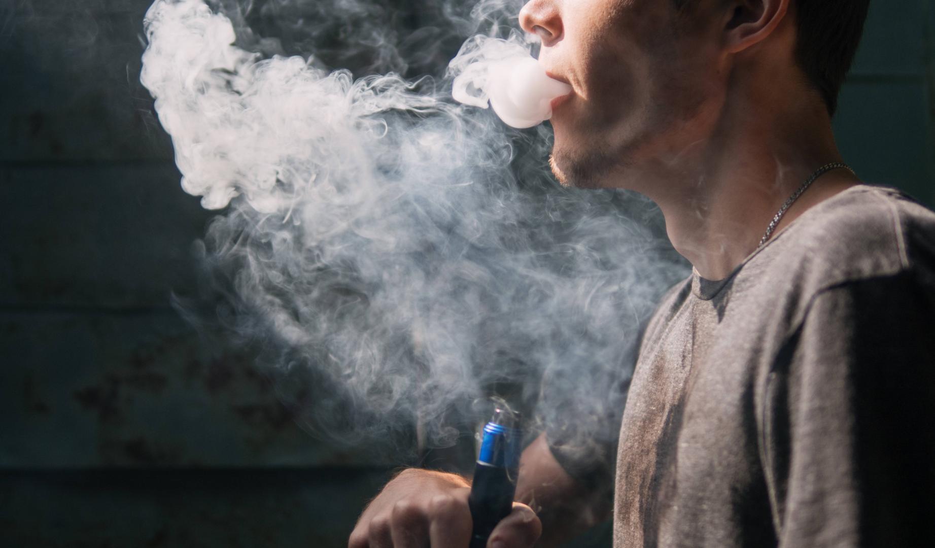 Un joven fuma un cigarrillo electrónico