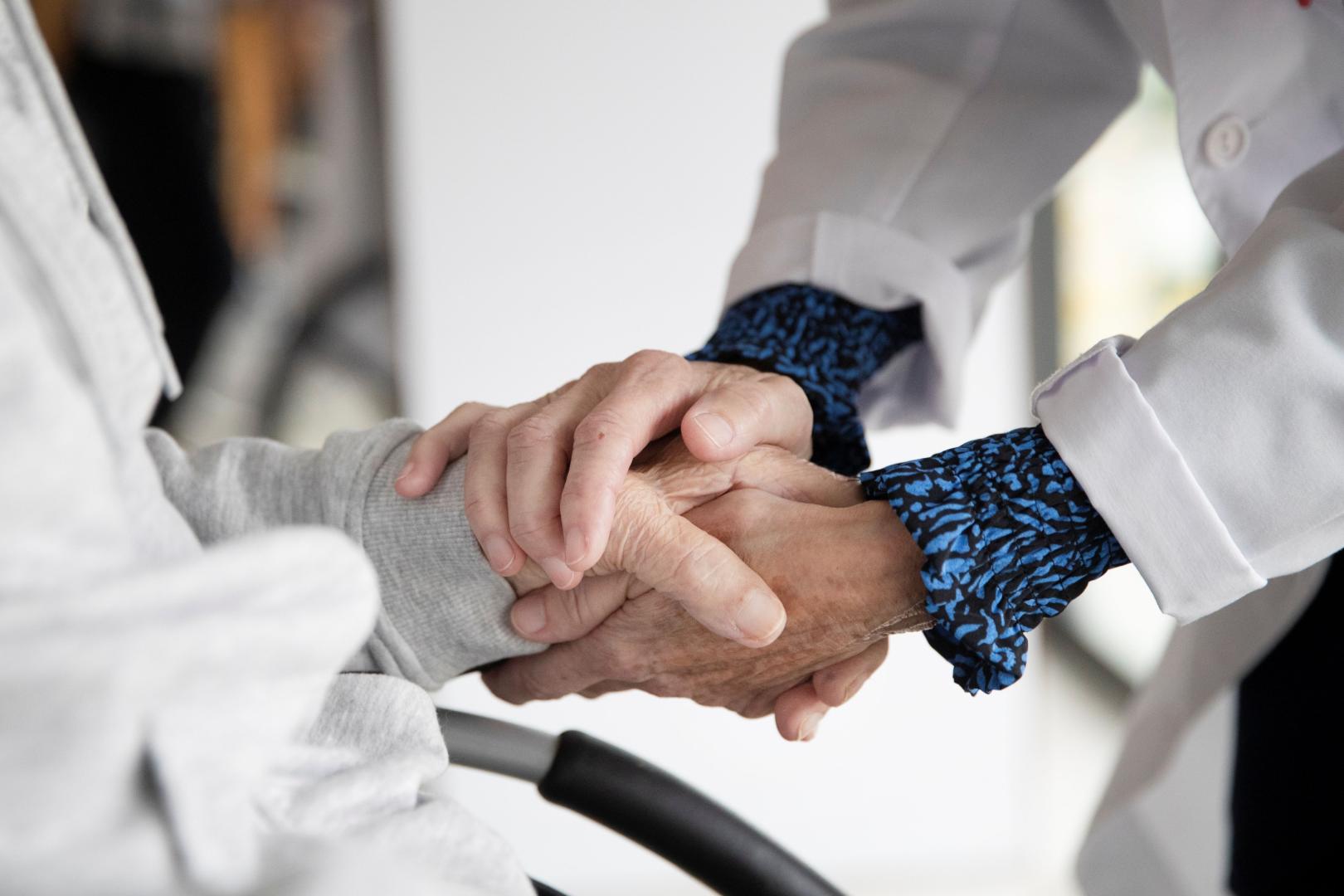 Una persona voluntaria da la mano a un paciente.