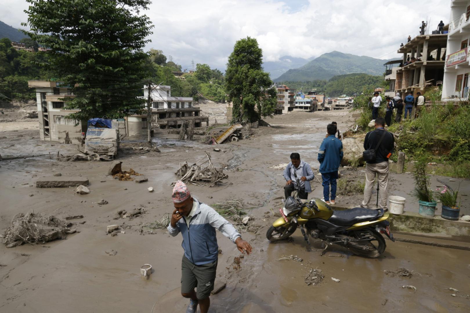 Varias personas caminan por las calles inundadas en Trishuli Bazar, en el distrito de Nuwakot