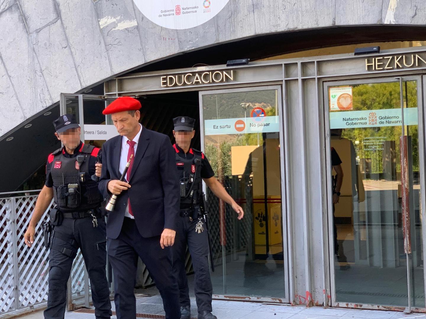 Ricardo Oficialdegui, con vestido de gaitero y con el instrumento en la mano, abandona la sede de Educación acompañado de dos agentes de la Policía Foral